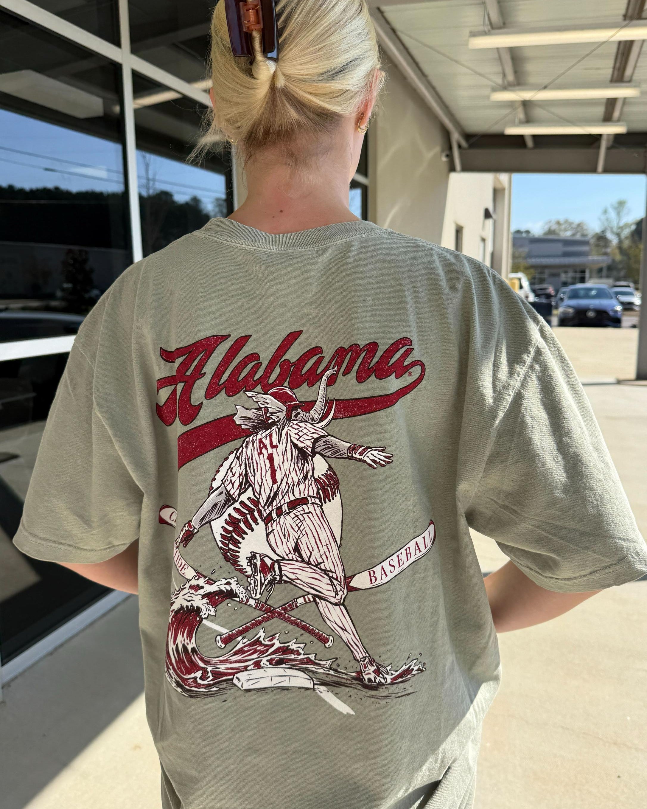 University of Alabama Tan T-Shirt with an image of Big Al running around a base with a Red Tidal Wave breaking over it and Red script “Alabama” above the image