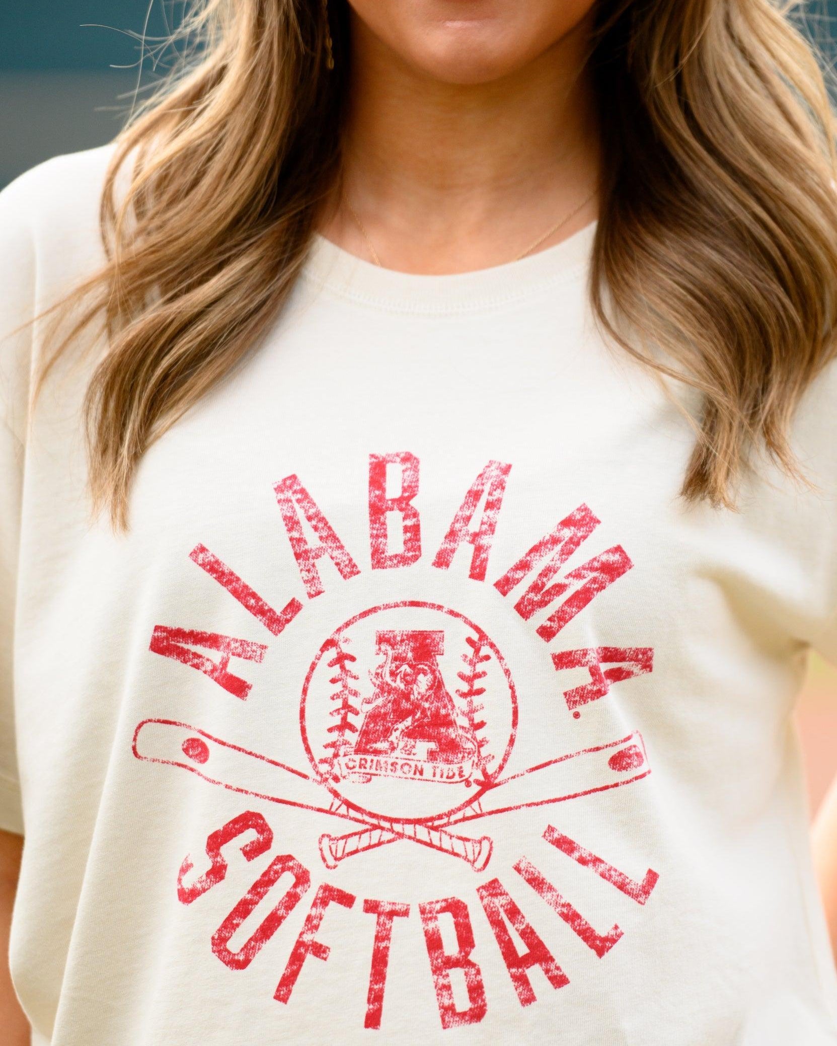 University of Alabama Distressed Ivory T-Shirt with a Red Softball featuring the Vintage A logo over crossed softball bats, surrounded by Red text “Alabama Softball”