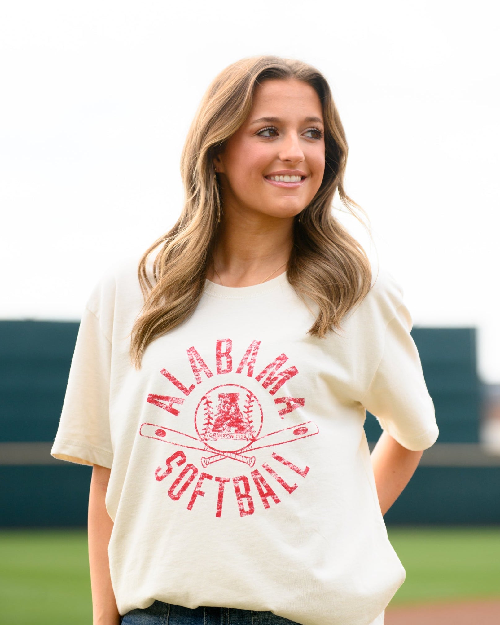 University of Alabama Distressed Ivory T-Shirt with a Red Softball featuring the Vintage A logo over crossed softball bats, surrounded by Red text “Alabama Softball”
