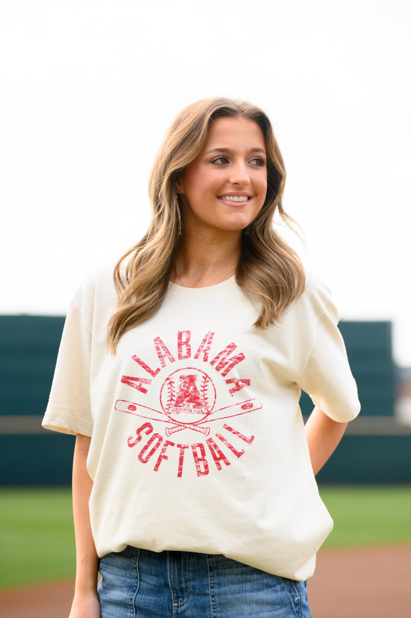 University of Alabama Distressed Ivory T-Shirt with a Red Softball featuring the Vintage A logo over crossed softball bats, surrounded by Red text “Alabama Softball”