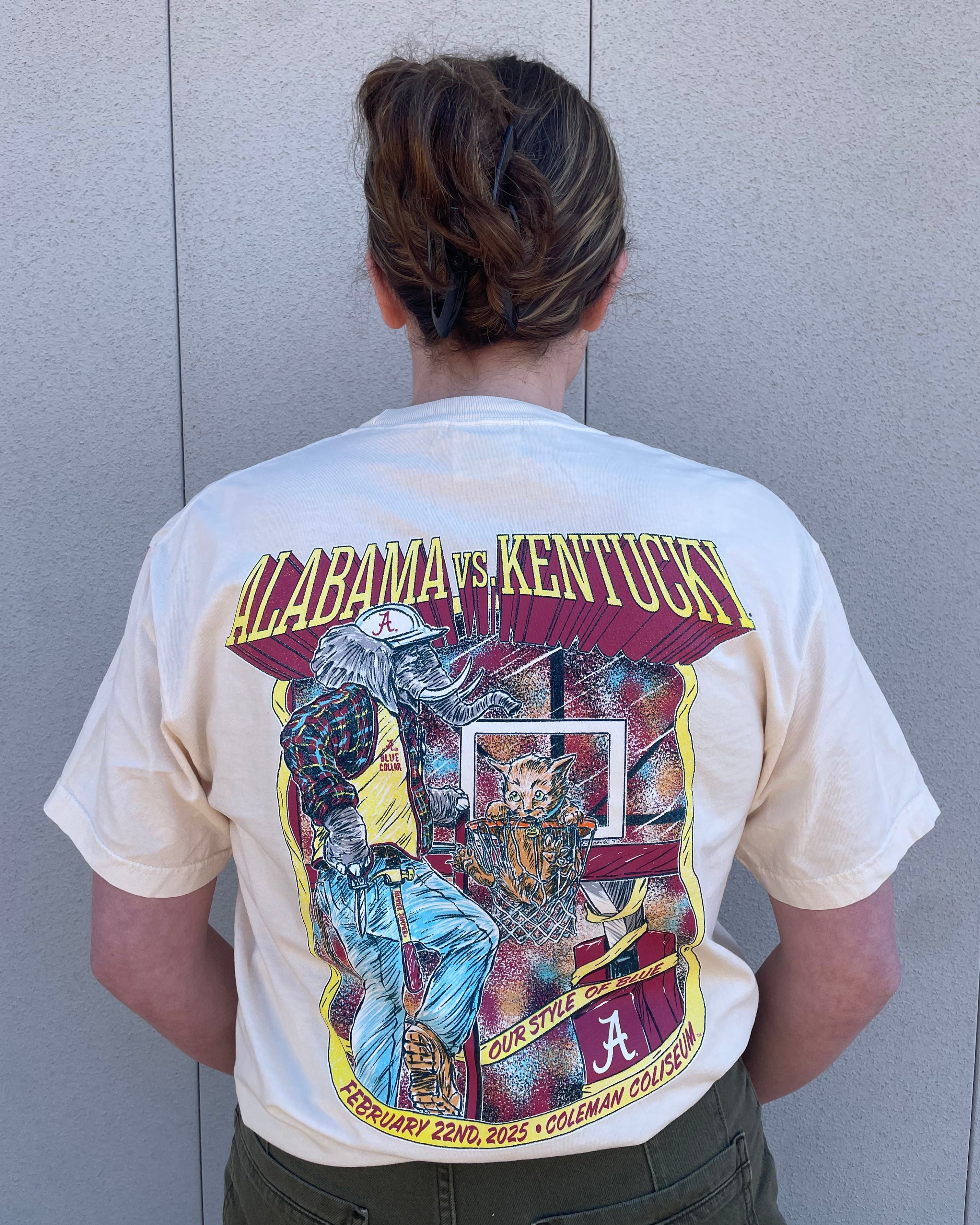 University of Alabama Alabama vs. Kentucky Basketball 2025 Ivory  Comfort Colors T-Shirt with Yellow text "Alabama vs. Kentucky" and an image of Big Al putting the Kentucky Wildcat into the Basketball Hoop