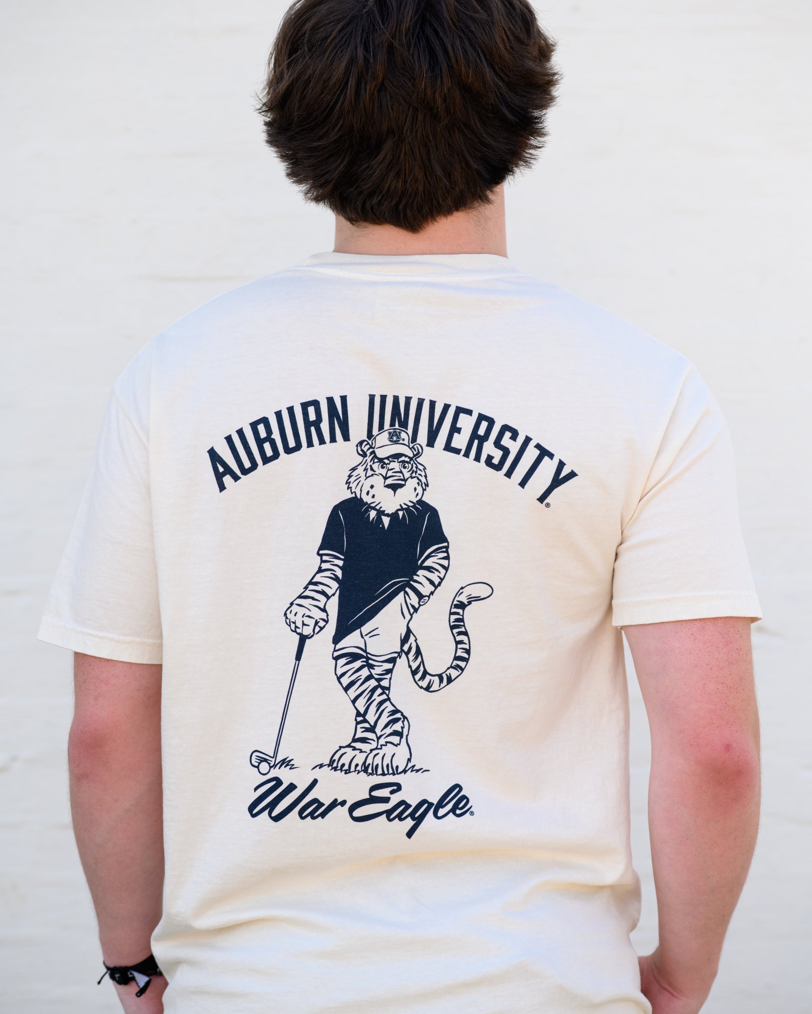 Auburn University Ivory T-Shirt with an image of Aubie leaning against a golf club between Navy Text "Auburn University" and "War Eagle"