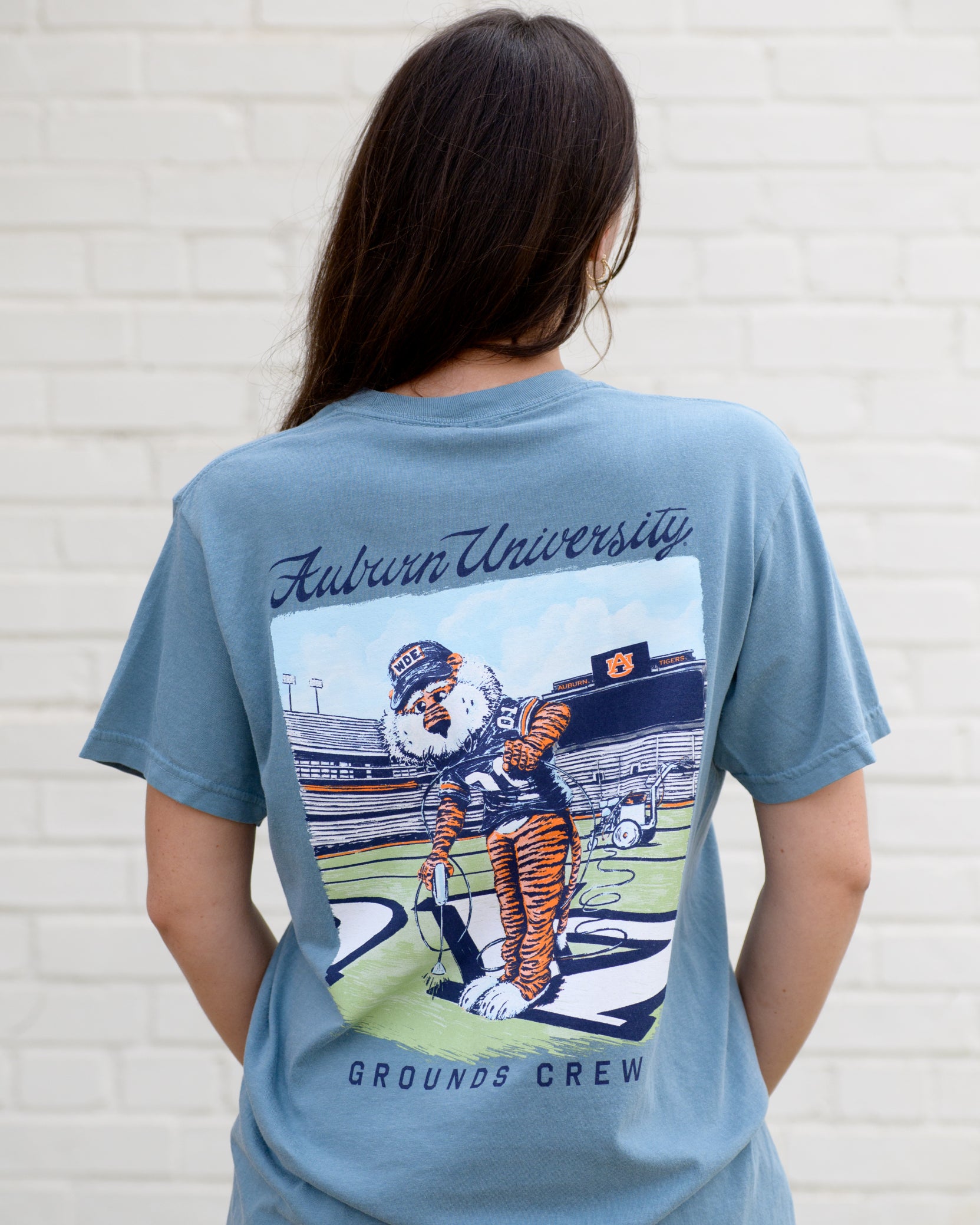 Auburn University Aubie Grounds Crew Ice Blue Comfort Colors T-Shirt with an image of Aubie the Tiger wearing a hat and painting the turf on the football field
