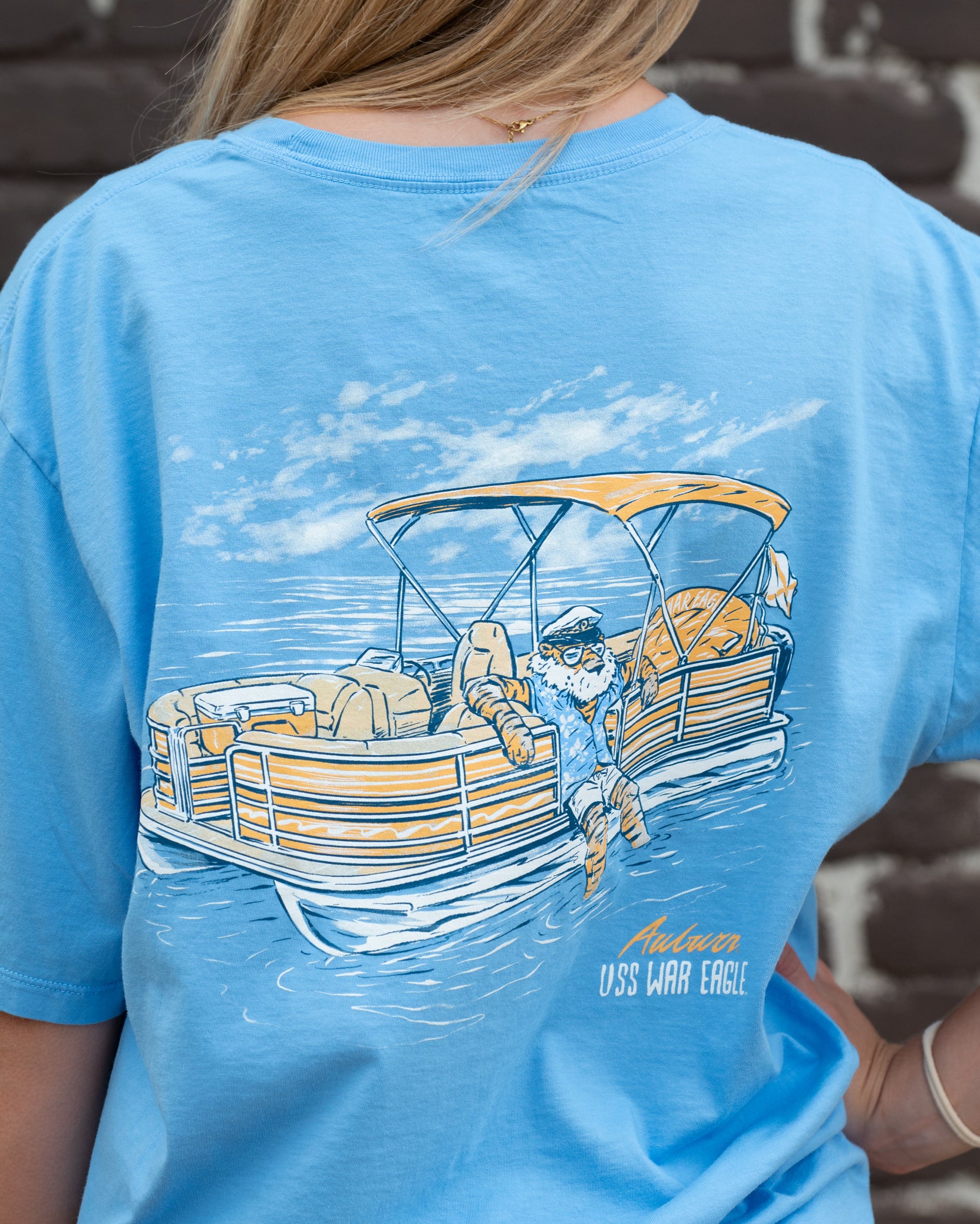Auburn University  Aubie Pontoon Azure Comfort Colors T-Shirt with an image of Aubie the Tiger lounging on the side of an Orange and White Pontoon Boat  with the text "USS WAR EAGLE" below