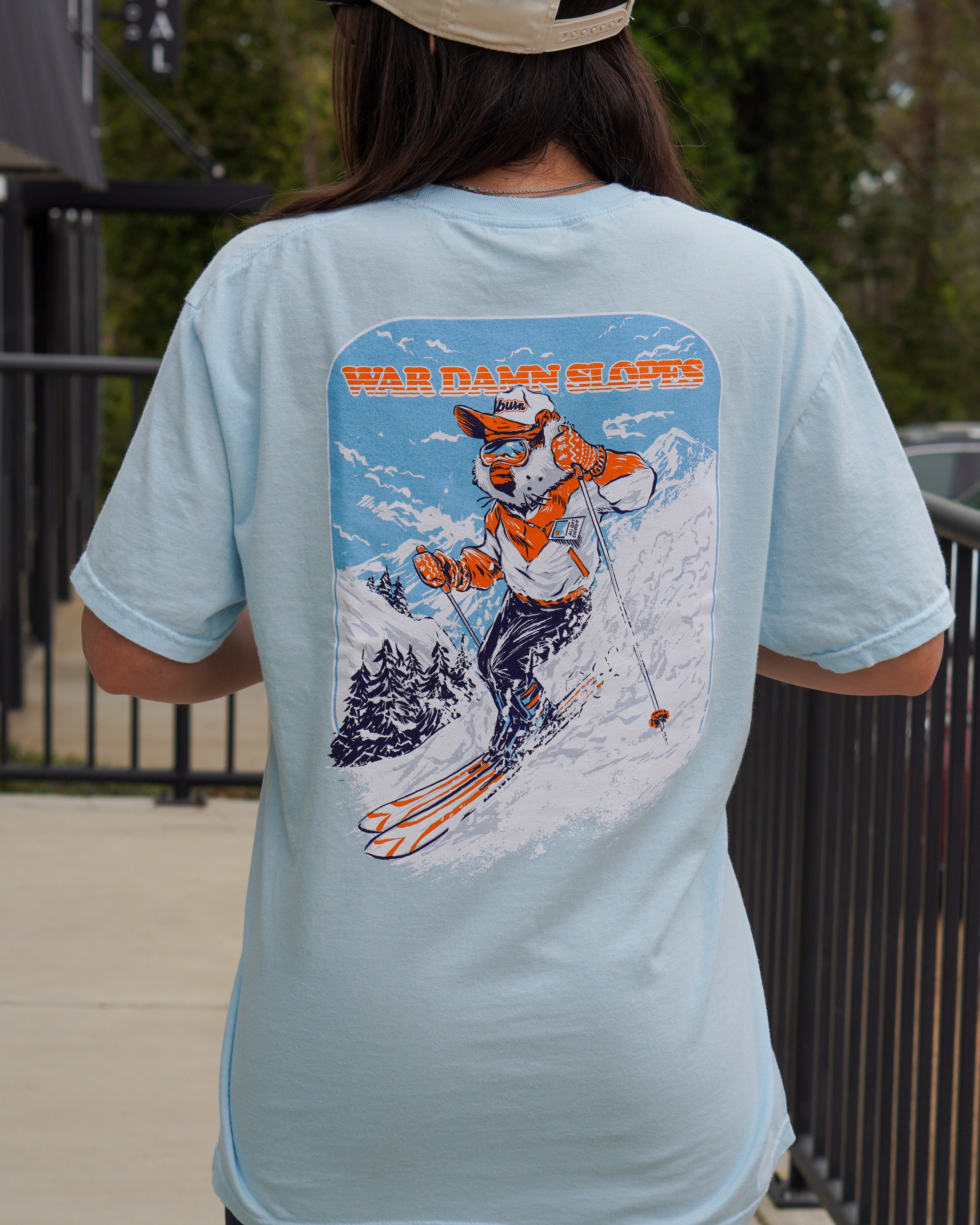 Auburn University Aubie Snow Skiing Chambray Comfort Colors T-Shirt with text "War Damn Slopes" above an image of Aubie in a ski outfit skiing down a snow-covered mountain