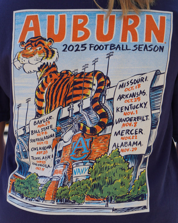 Auburn University Navy T-Shirt with an image of Aubie laying on the stadium and painting the Auburn football schedule on two banners