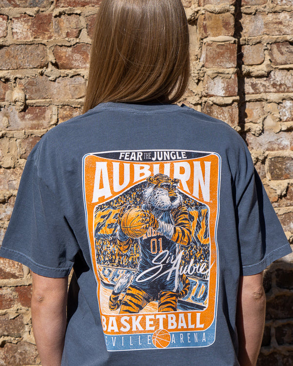 Auburn University Dark Blue T-Shirt with a basketball card style design featuring Aubie dribbling a basketball down the court in between text “Fear the Jungle Auburn” and “Basketball Neville Arena” and with an autograph from “Sir Aubie”