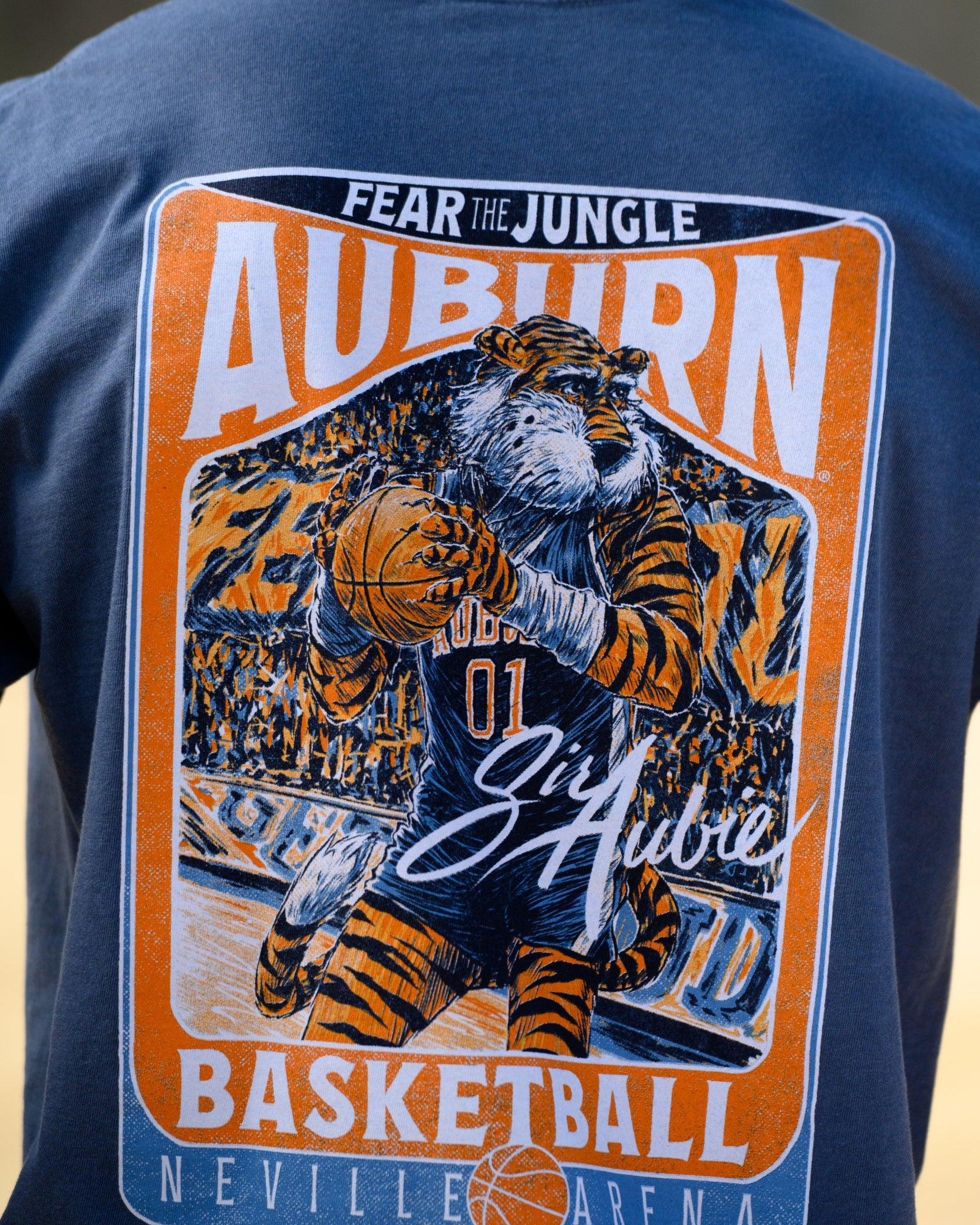 Auburn University Dark Blue T-Shirt with a basketball card style design featuring Aubie dribbling a basketball down the court in between text “Fear the Jungle Auburn” and “Basketball Neville Arena” and with an autograph from “Sir Aubie”
