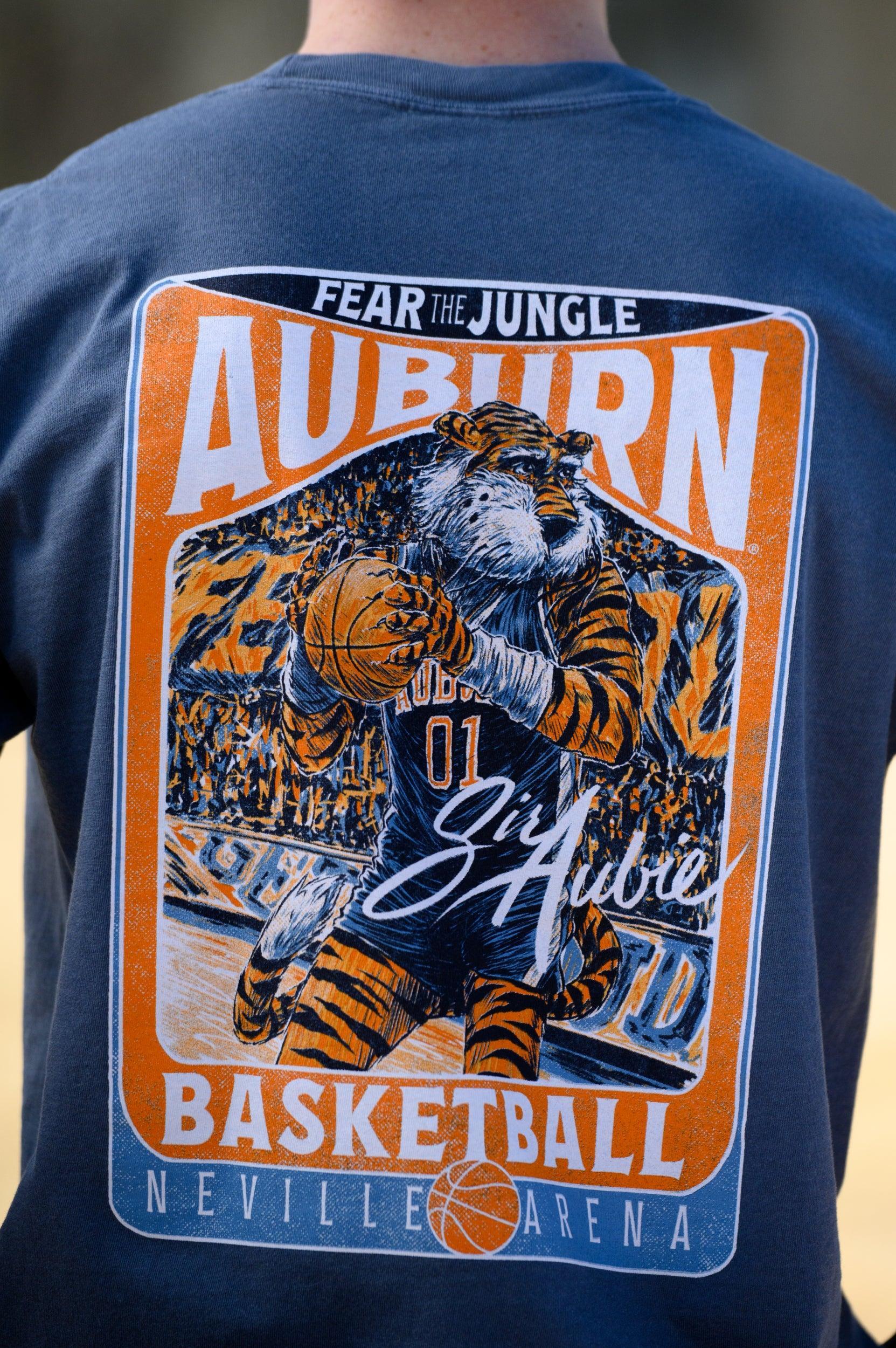 Auburn University Dark Blue T-Shirt with a basketball card style design featuring Aubie dribbling a basketball down the court in between text “Fear the Jungle Auburn” and “Basketball Neville Arena” and with an autograph from “Sir Aubie”