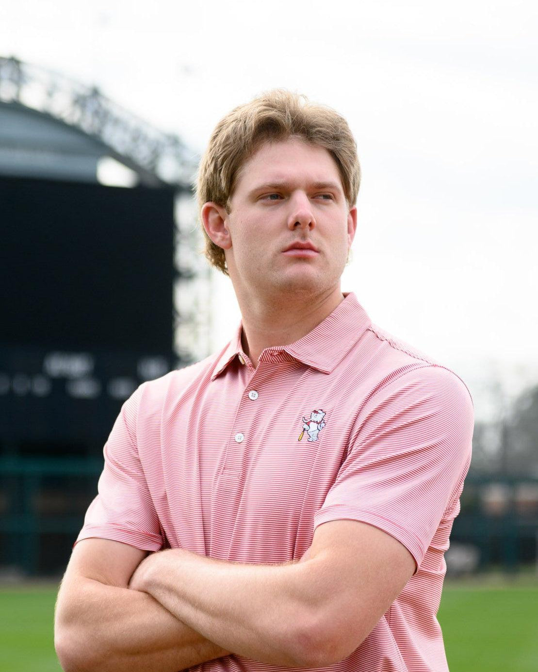 University of Alabama Men's Crimson Stripe Performance Polo with an embroidered image of Big Al in a baseball uniform leaning on a baseball bat