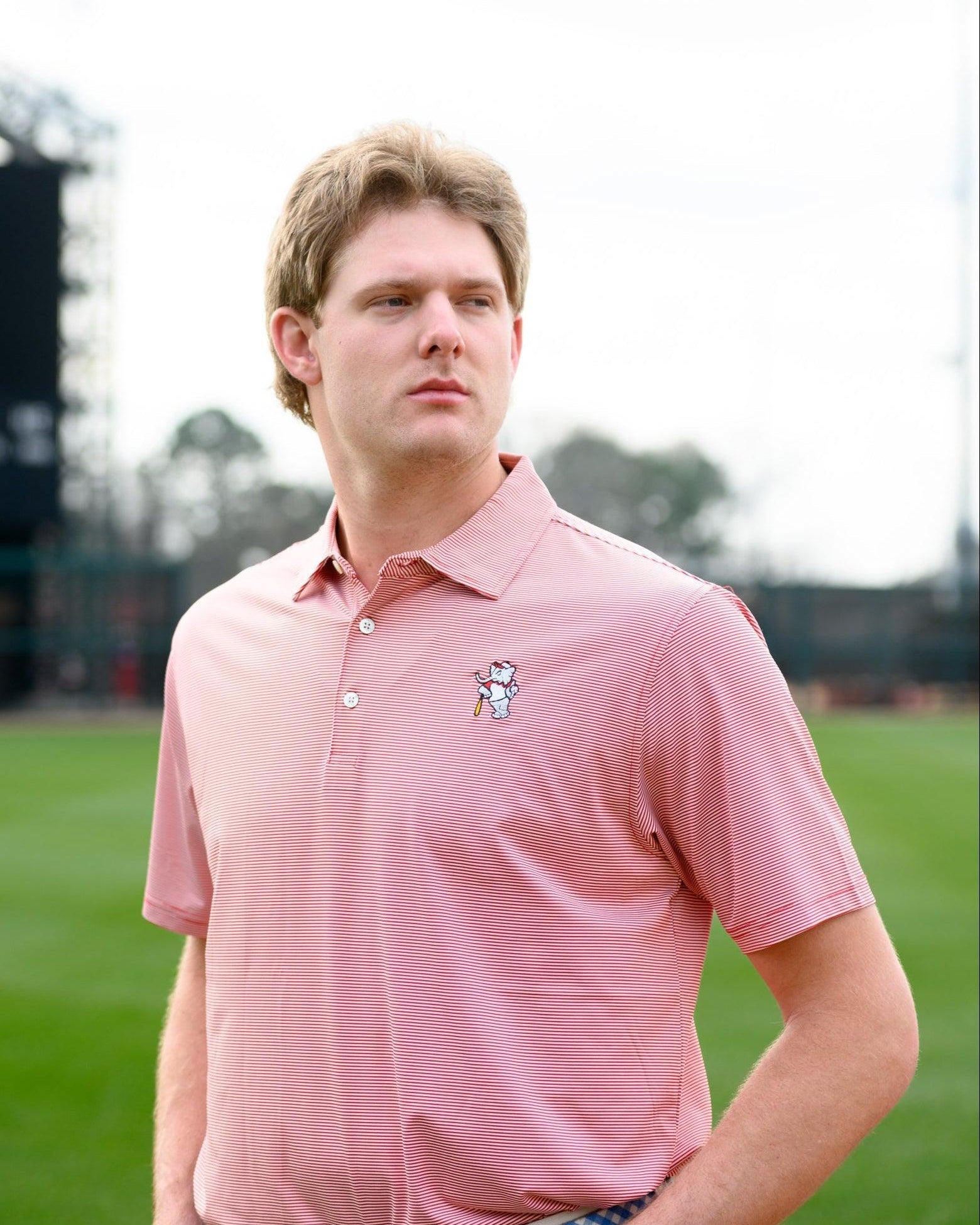 University of Alabama Men's Crimson Stripe Performance Polo with an embroidered image of Big Al in a baseball uniform leaning on a baseball bat