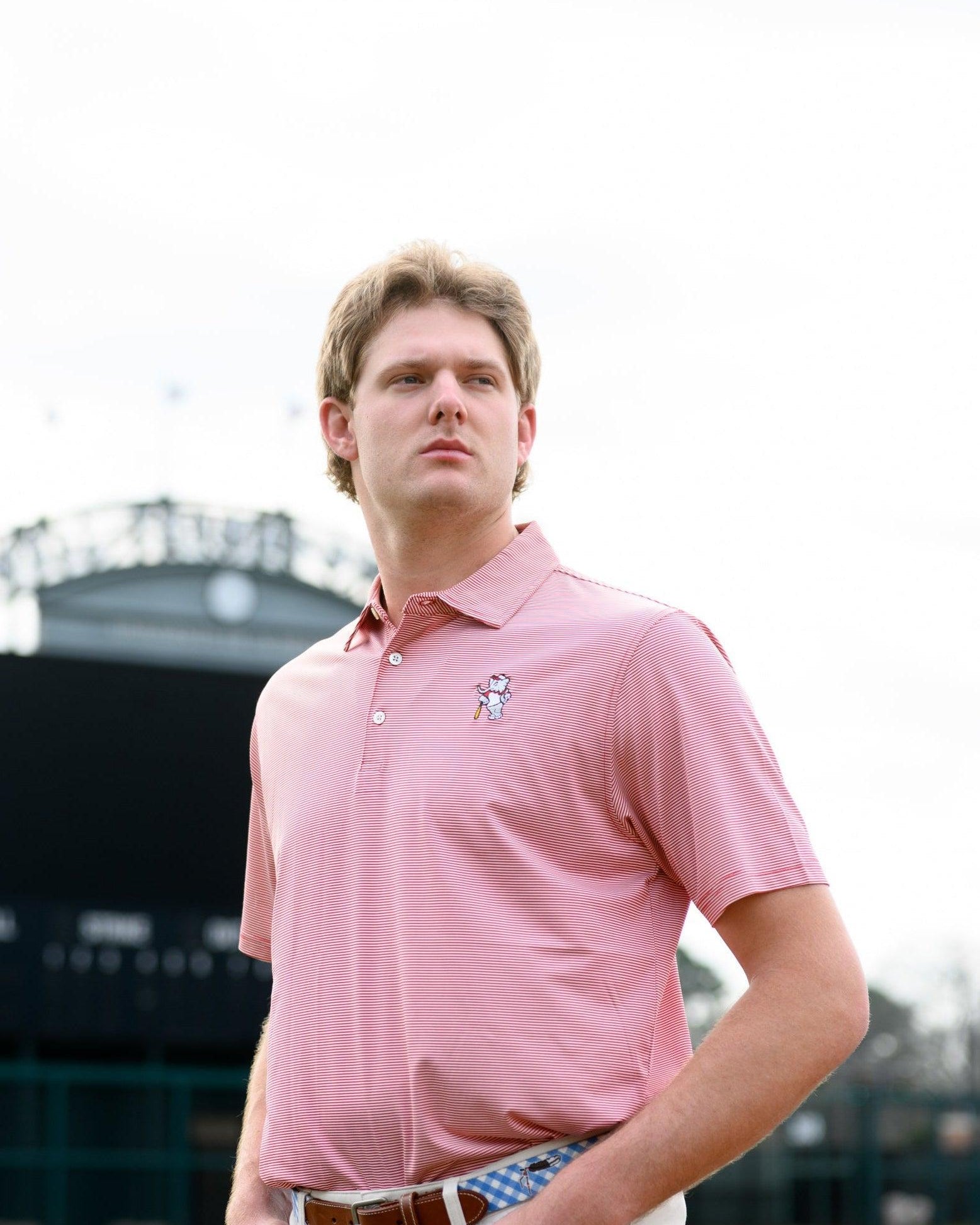 University of Alabama Men's Crimson Stripe Performance Polo with an embroidered image of Big Al in a baseball uniform leaning on a baseball bat