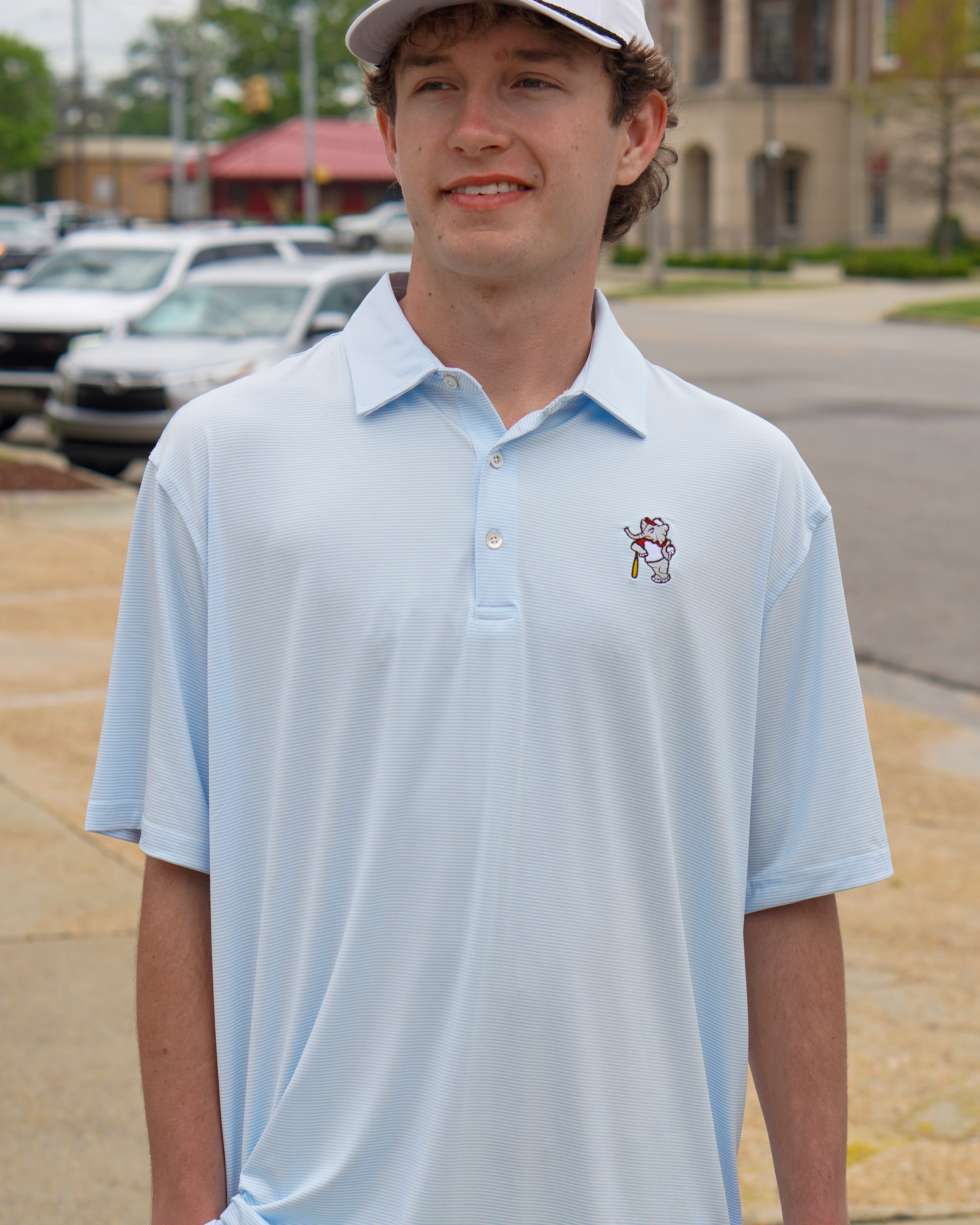 University of Alabama BallPlayer Al Men's Light Blue Performance Polo with an embroidered image of Big Al in a baseball uniform leaning on a baseball bat