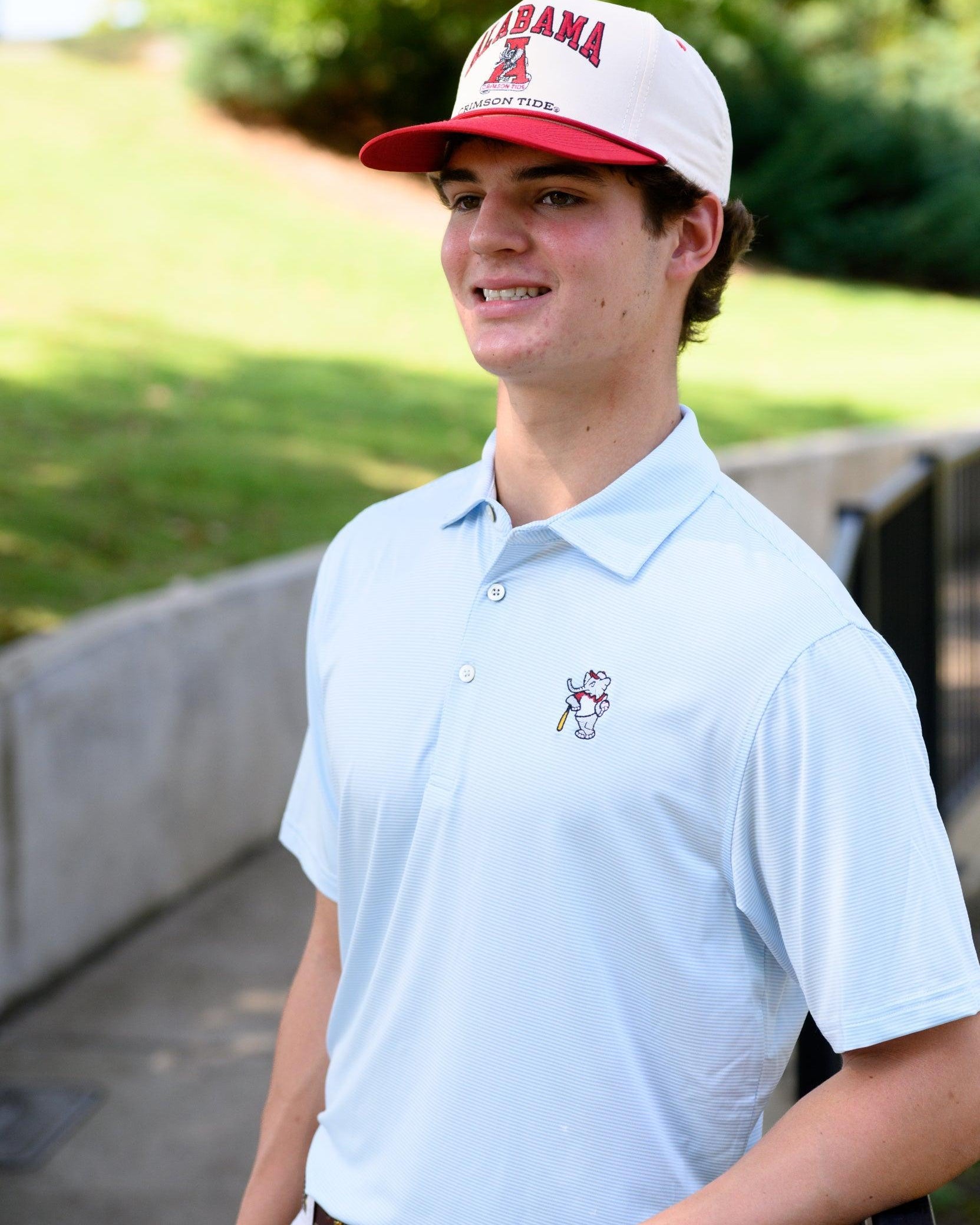 University of Alabama BallPlayer Al Men's Light Blue Performance Polo with an embroidered image of Big Al in a baseball uniform leaning on a baseball bat