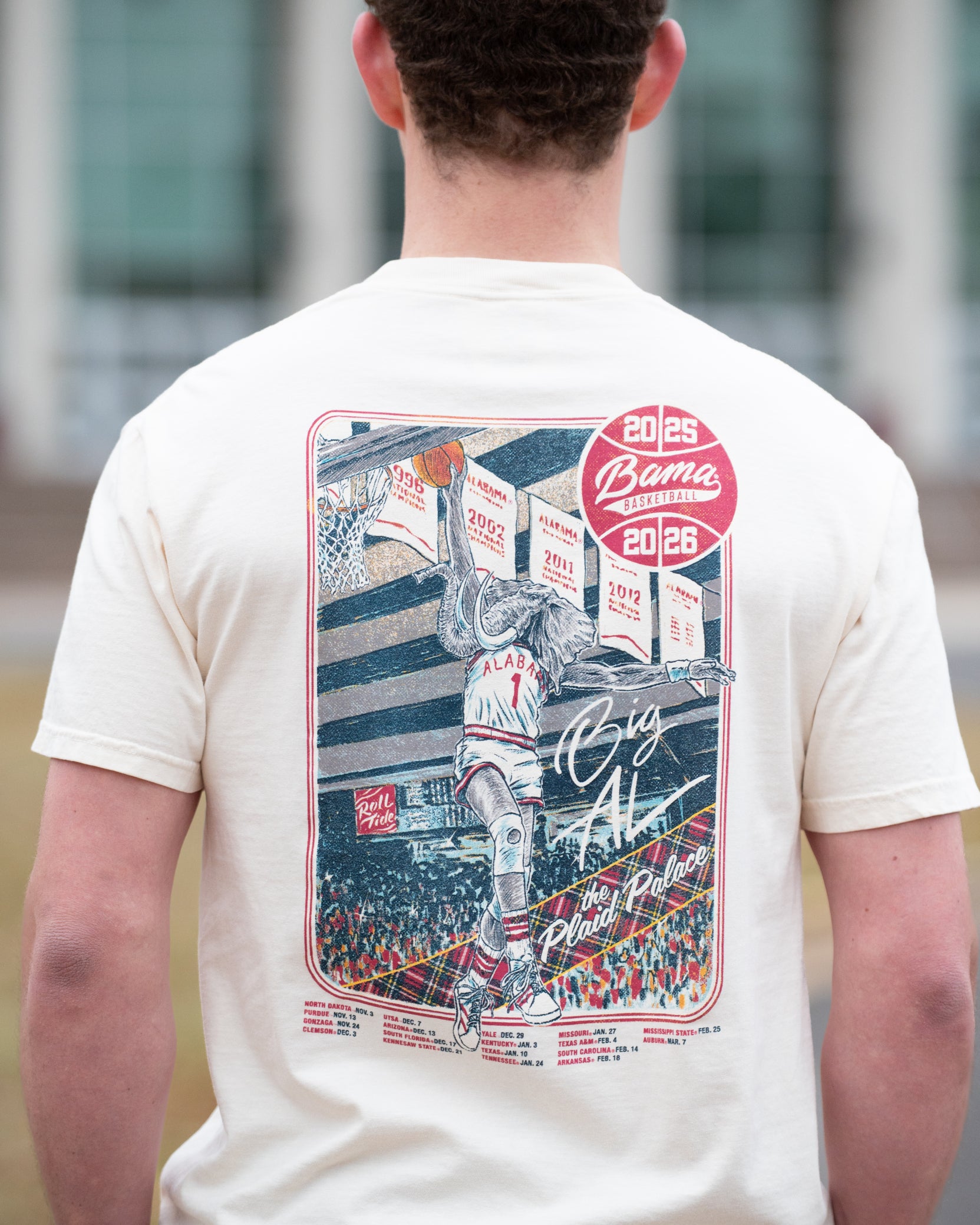 University of Alabama Ivory Shirt with an illustration of Big Al dunking a basketball next to text “Big Al” and “the Plaid Palace” above the 2025 Basketball Schedule