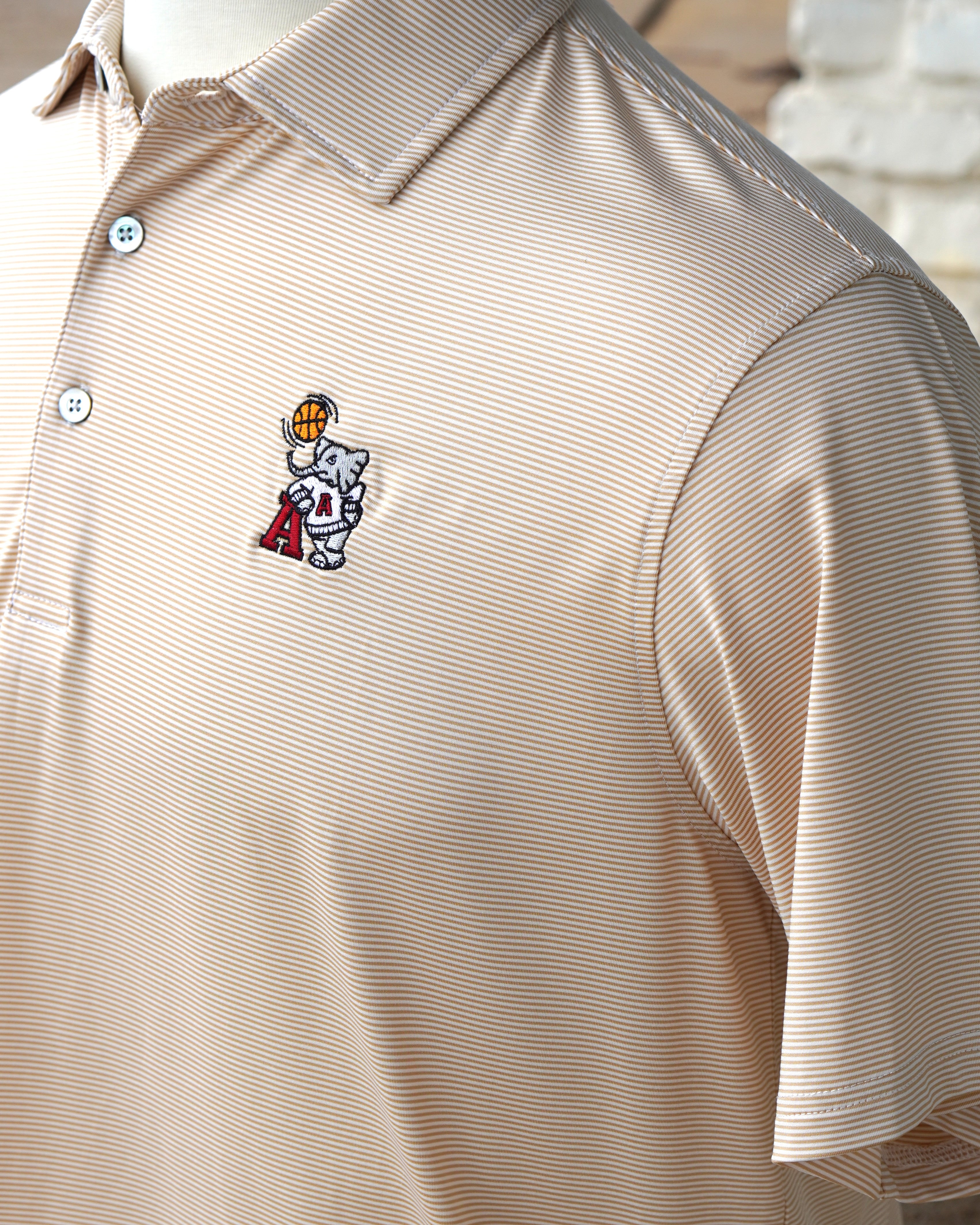 University of Alabama Basketball Al Tan Men’s Polo with an embroidered Big Al in a sweater holding a basketball and leaning against an "A"