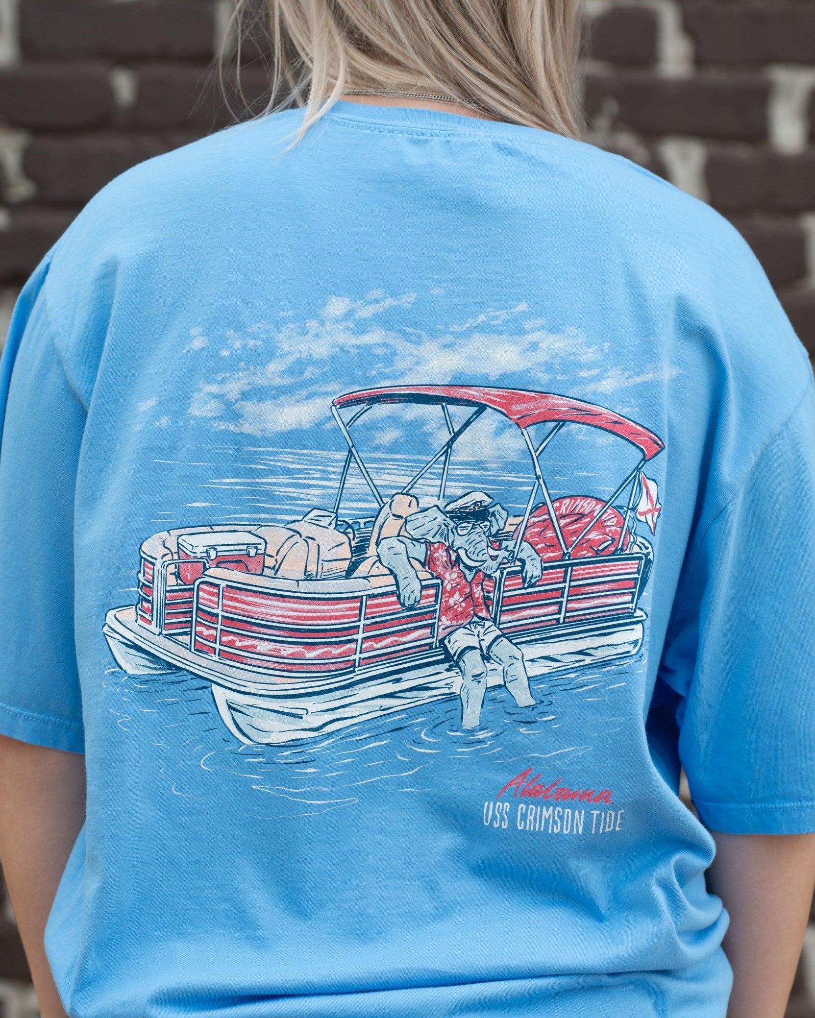University of Alabama Big Al Pontoon Azure Comfort Colors T-Shirt with an image of Big Al lounging on the side of a Red and White Pontoon Boat with the text "USS Crimson Tide" below