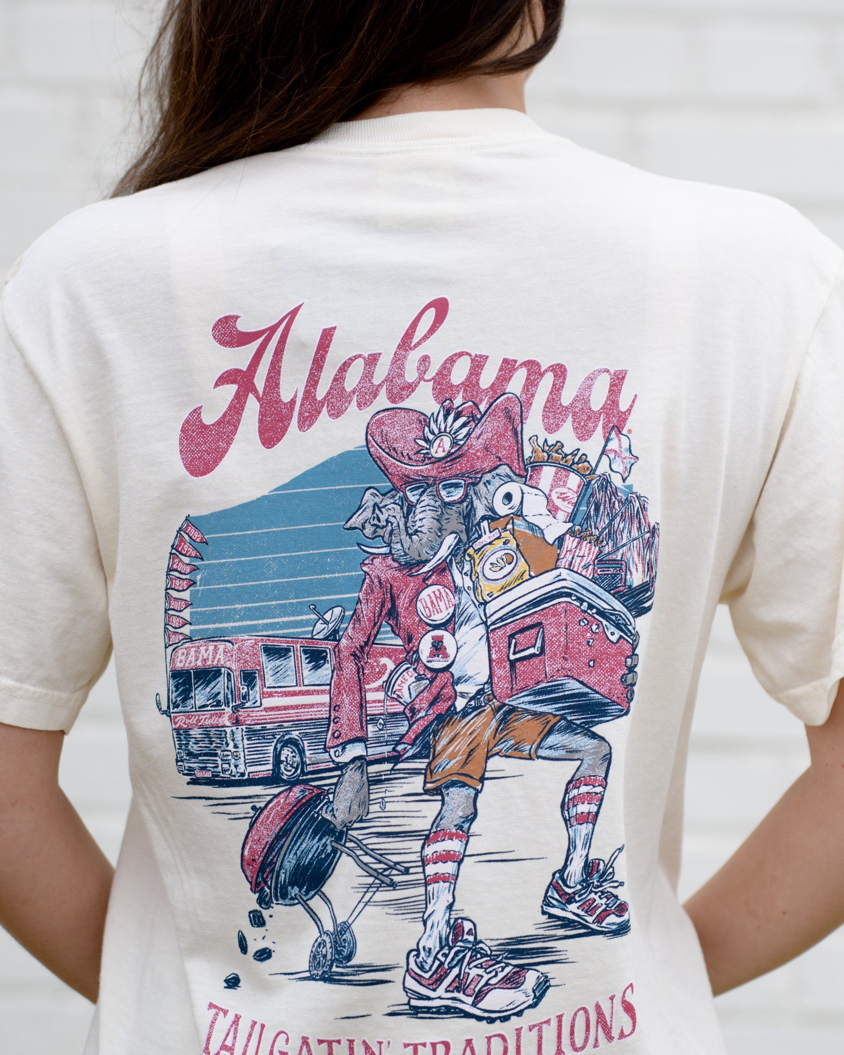 University of Alabama Cream Big Al Tailgate Comfort Colors T-Shirt with an image of Big Al in Gameday Gear with a cooler and a grill above text "Tailgatin' Traditions"