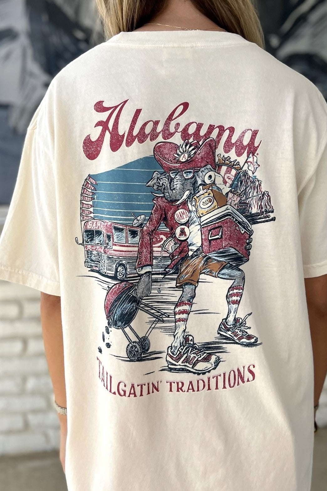 University of Alabama Cream Big Al Tailgate Comfort Colors T-Shirt with an image of Big Al in Gameday Gear with a cooler and a grill above text "Tailgatin' Traditions"