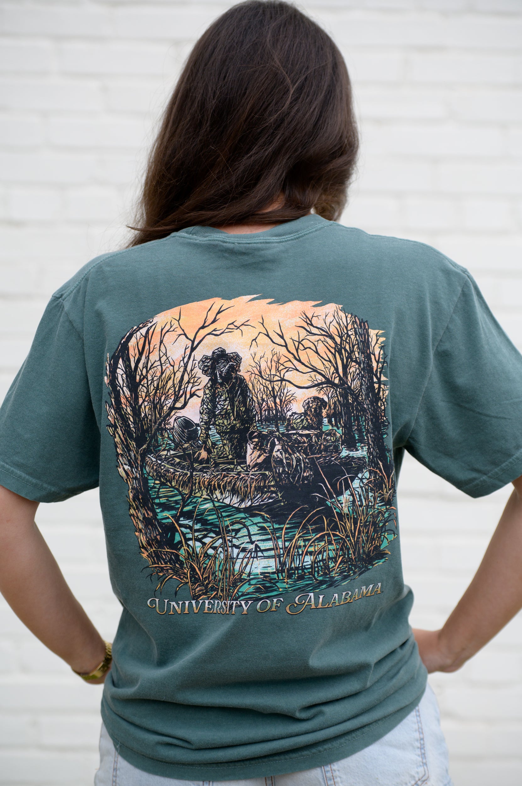 University of Alabama Big Al Duck Hunt Blue Spruce Comfort Colors T-Shirt with an image of Big Al wearing hunting gear with a dog in a boat in the swamp