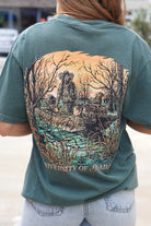 University of Alabama Big Al Duck Hunt Blue Spruce Comfort Colors T-Shirt with an image of Big Al wearing hunting gear with a dog in a boat in the swamp