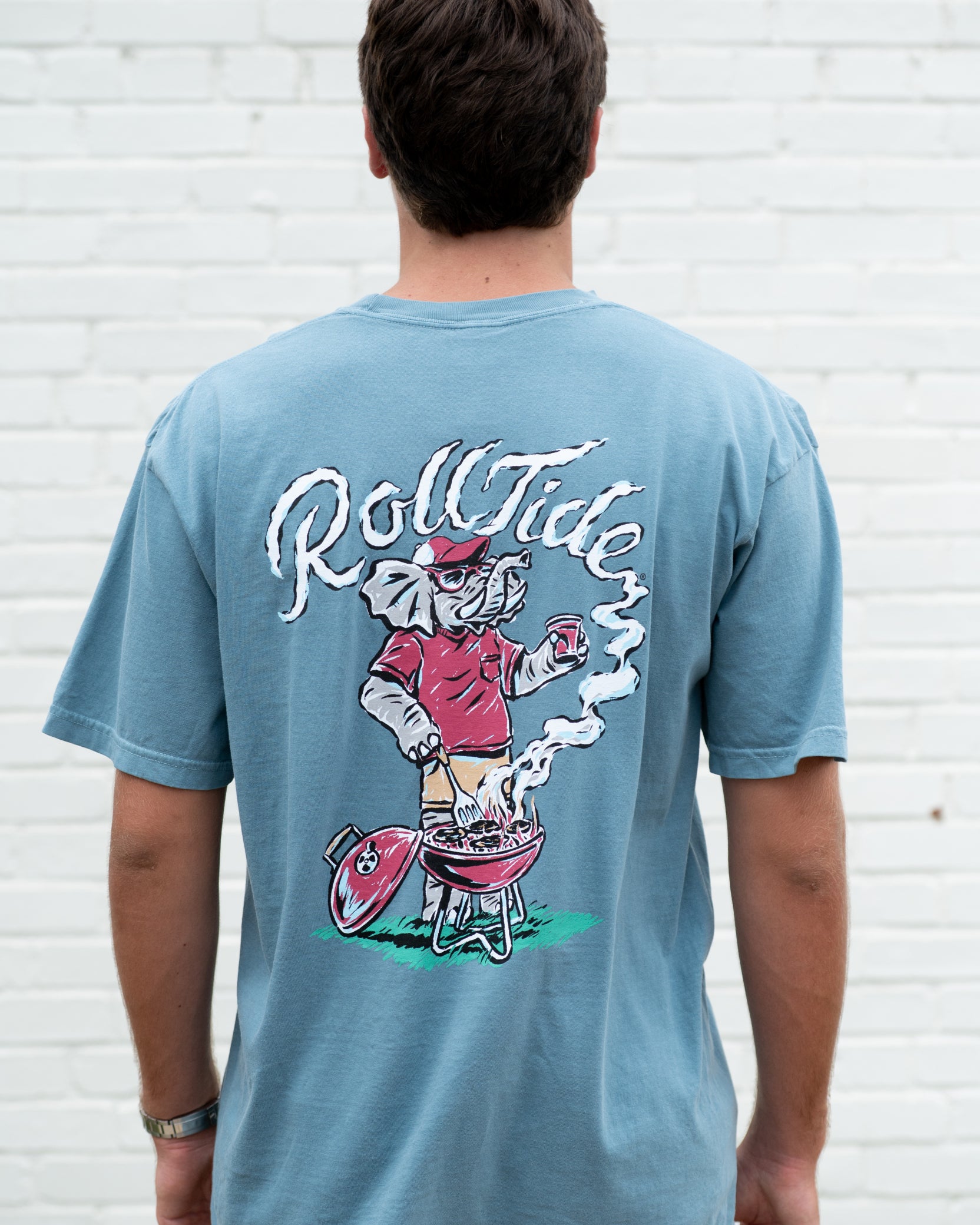University of Alabama Blue T-Shirt with a drawing of Big Al grilling and the words “Roll Tide” written in the smoke