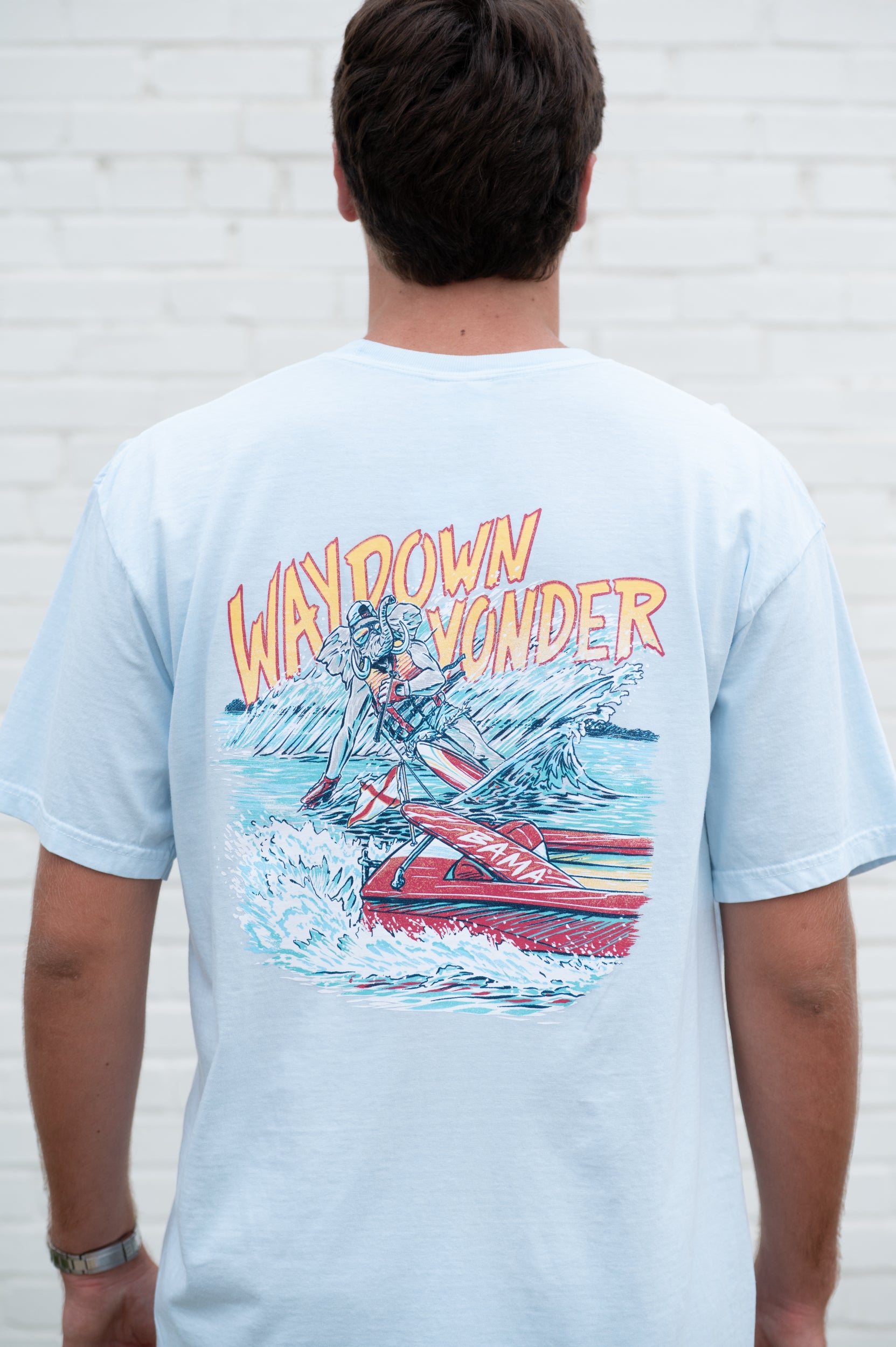 University of Alabama Baby Blue T-Shirt with Yellow text “Way Down Yonder” above an image of Big Al water skiing