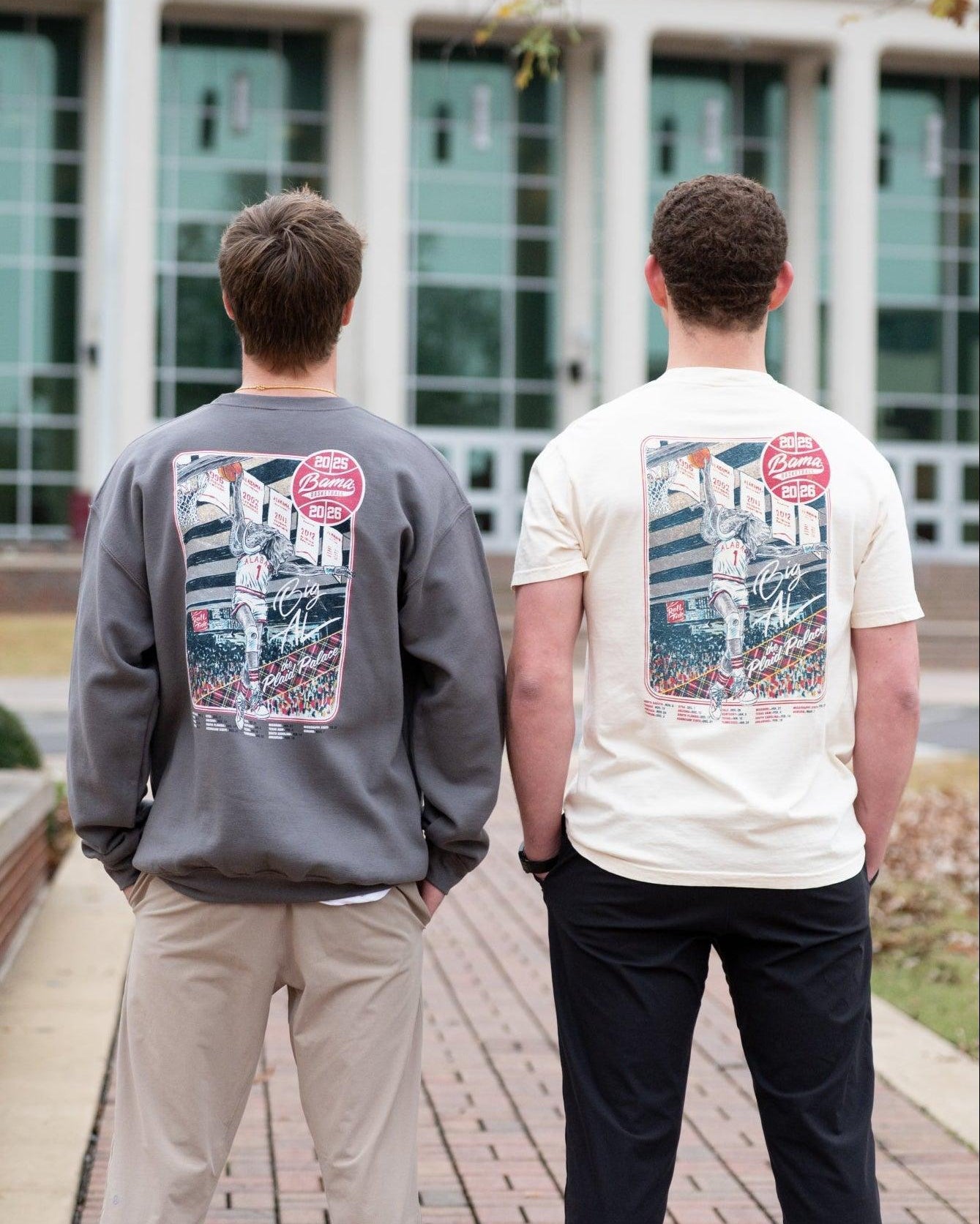 Two people wearing sweatshirts with stadium graphics outdoors.