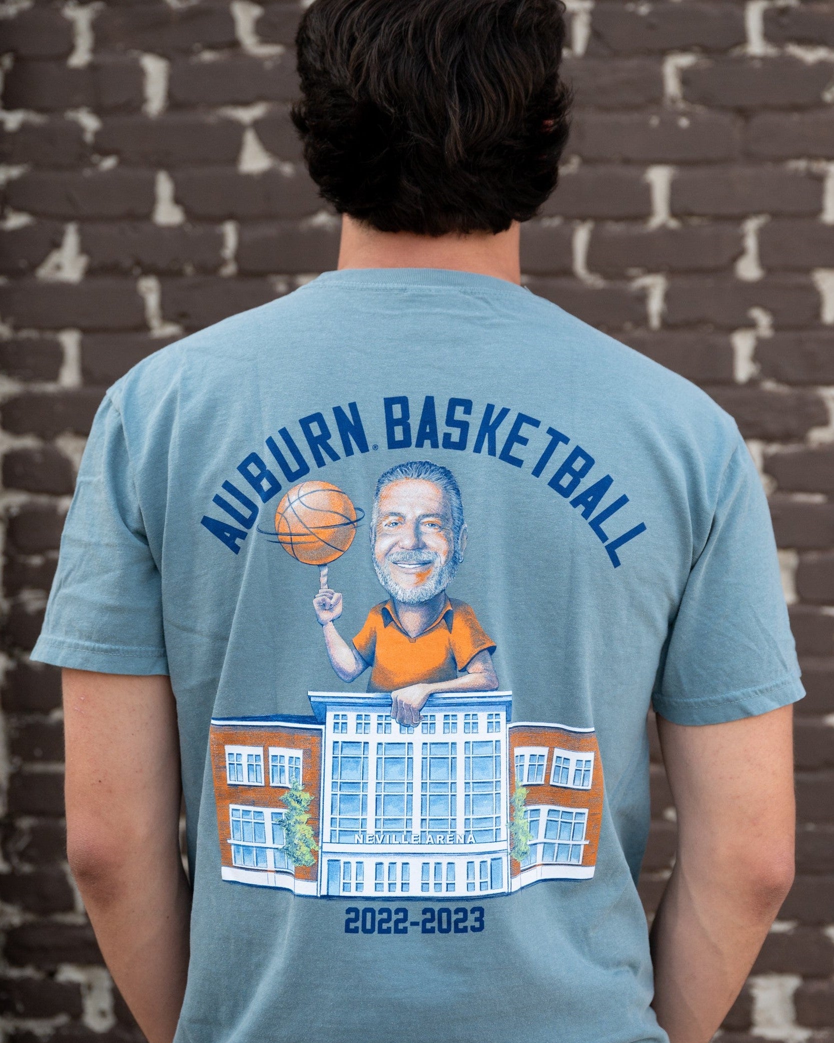 Auburn University Blue Bruce Pearl 2023 Comfort Colors T-Shirt with Navy text "Auburn Basketball" above an image of Auburn Basketball Coach Bruce Pearl spinning a basketball and leaning on the basketball building