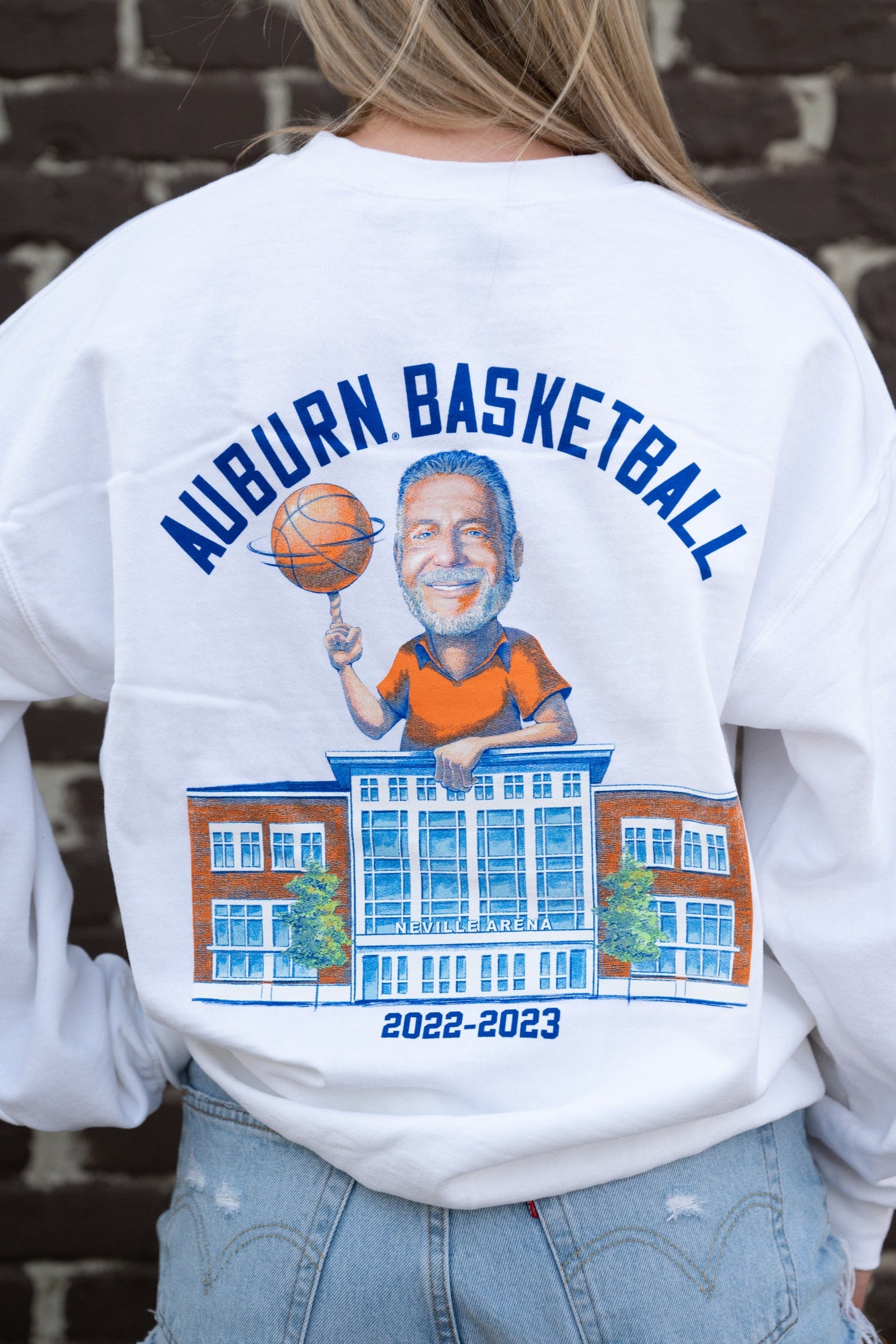 Auburn University White Bruce Pearl 2023 Gildan Sweatshirt with Navy text "Auburn Basketball" above an image of Auburn Basketball Coach Bruce Pearl spinning a basketball and leaning on the basketball building