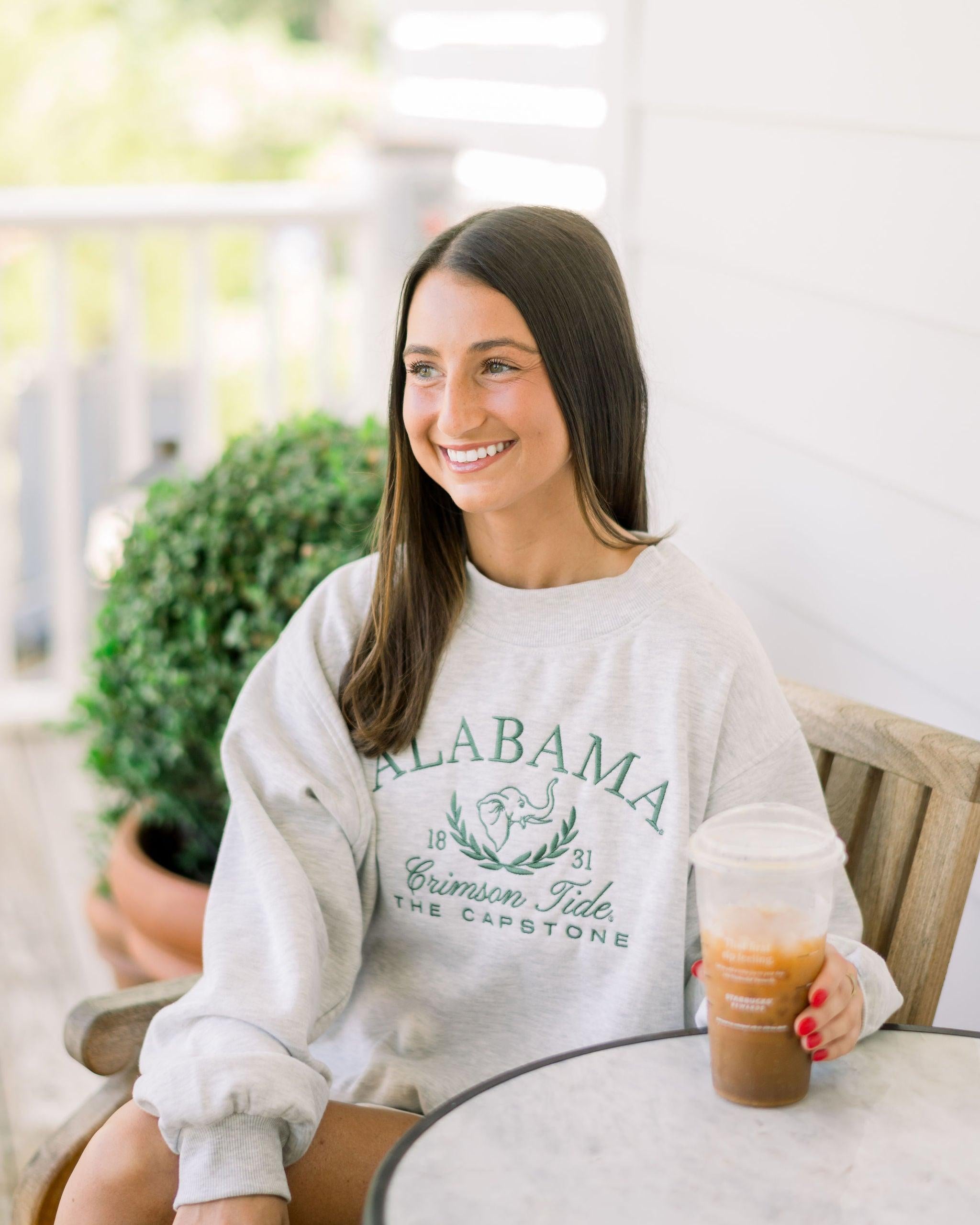 University of Alabama Grey Mock Neck Sweatshirt with Green Embroidered text “Alabama” above the elephant crest (An elephant head outline encircled by a wreath of laurels), and text “Crimson Tide- The Capstone”