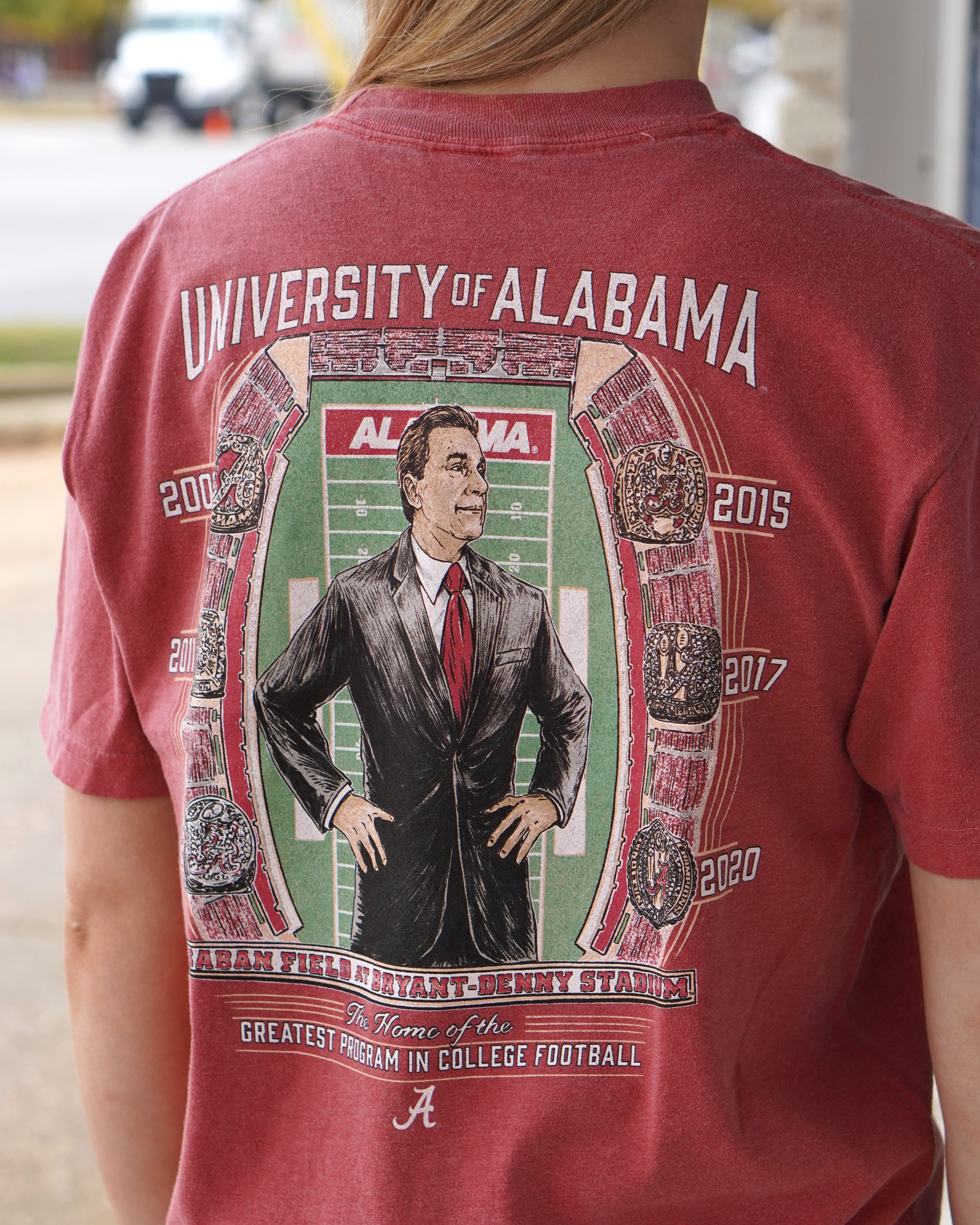 University of Alabama Champion Legacy at Saban Field Red Comfort Colors T-Shirt with an image of Nick Saban standing over Bryant-Denny Stadium surrounded by the years Alabama won the Football Championship