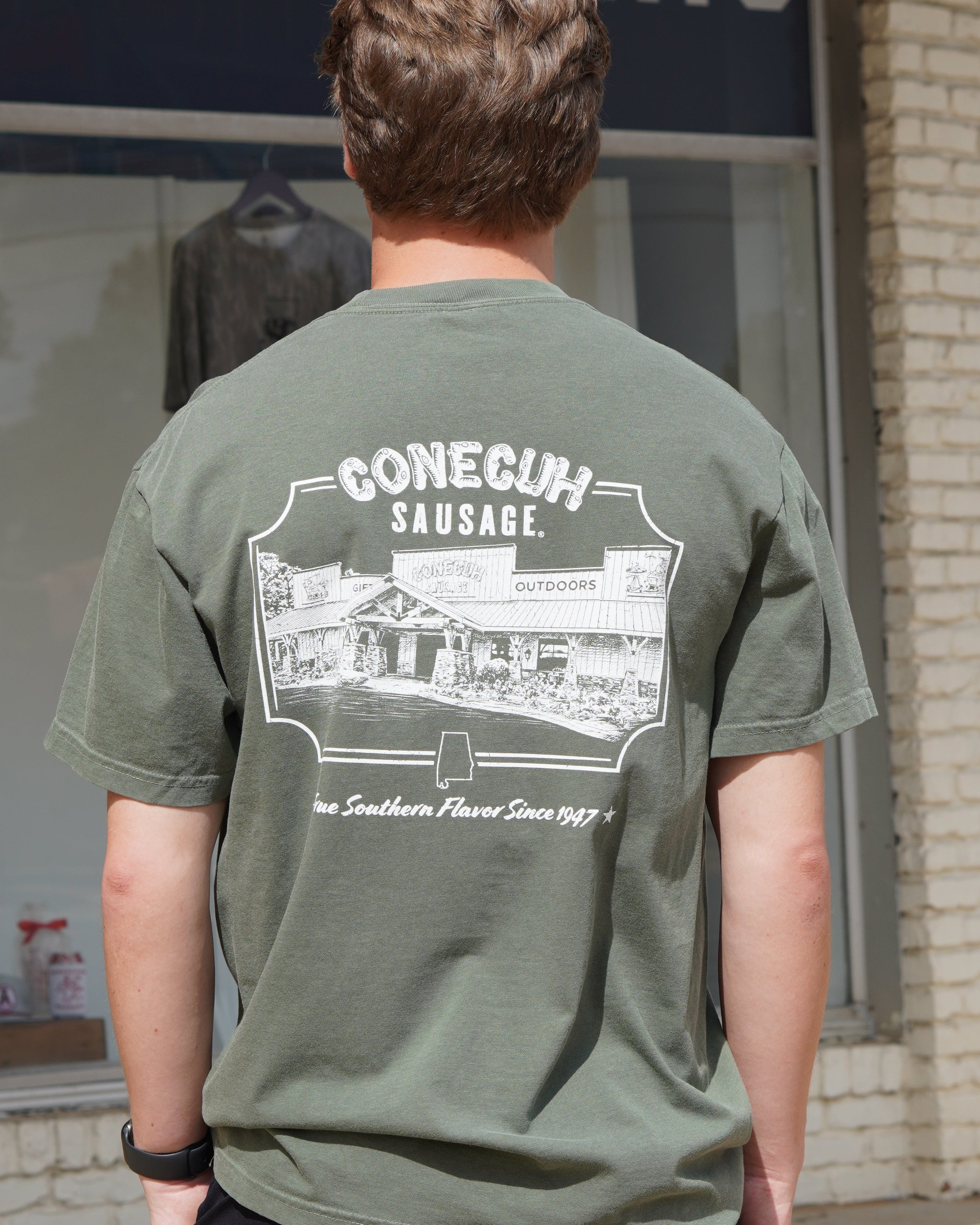 Conecuh Dark Green Shirt with an illustration of the old Conecuh Sausage building