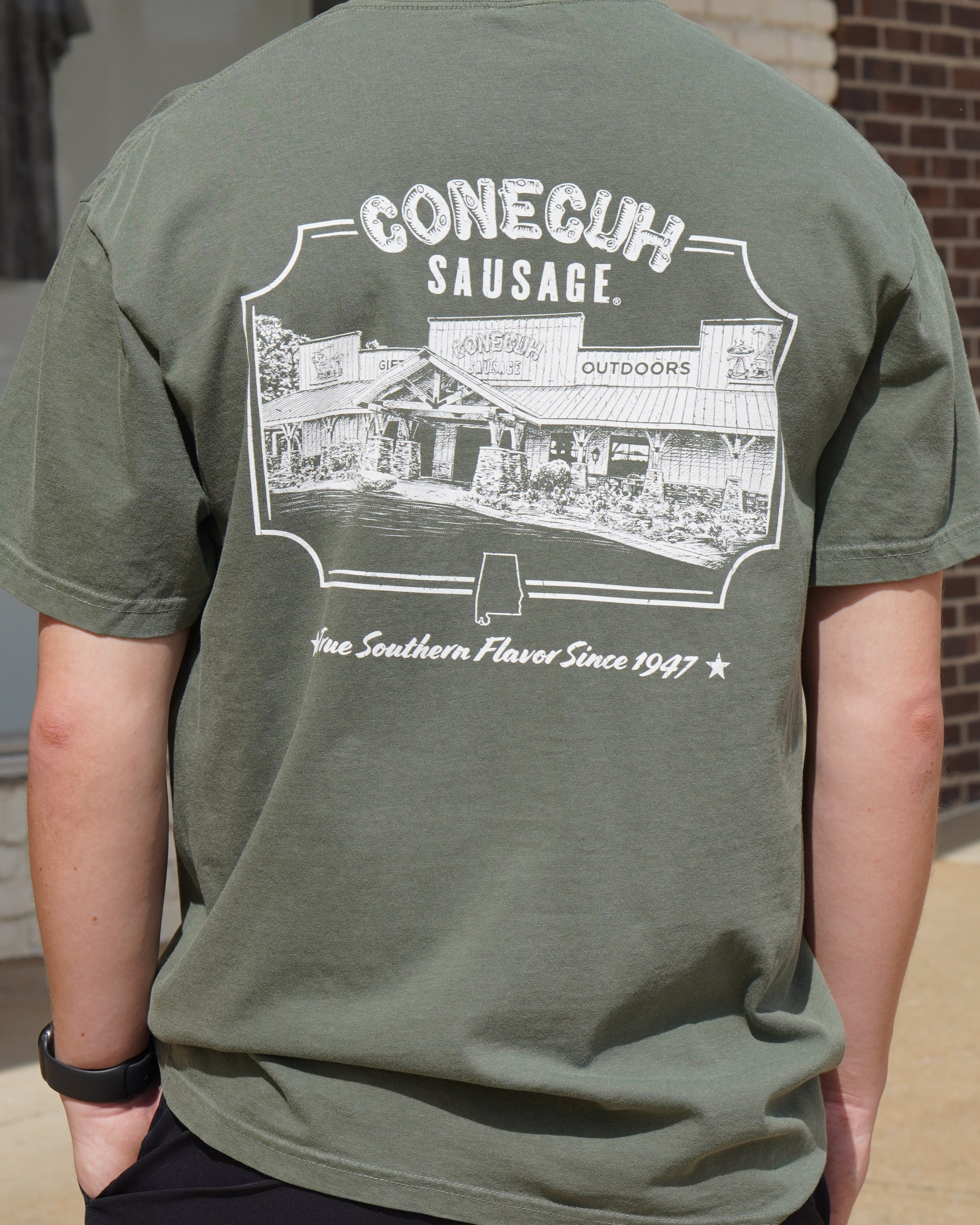 Conecuh Dark Green Shirt with an illustration of the old Conecuh Sausage building