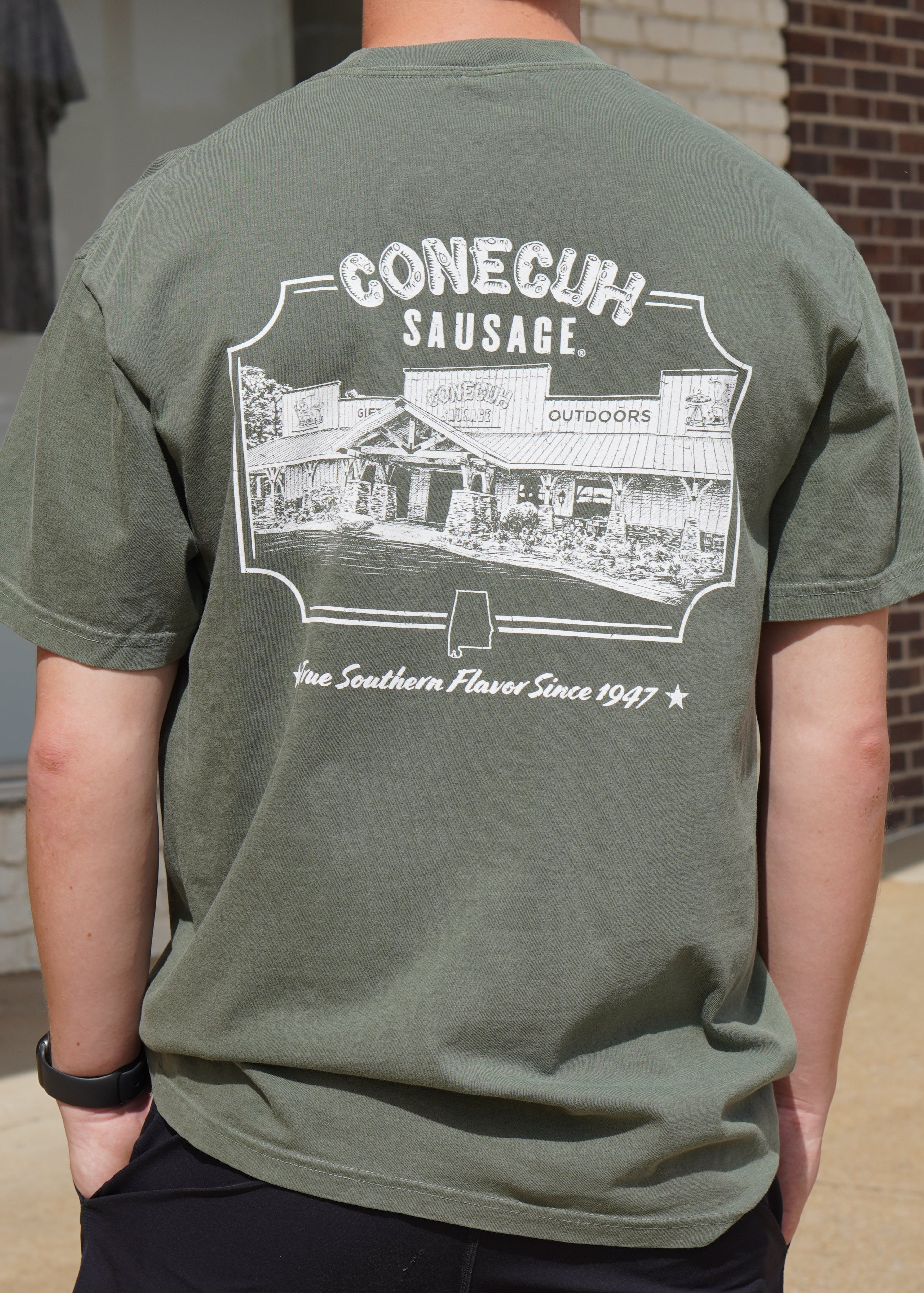 Conecuh Dark Green Shirt with an illustration of the old Conecuh Sausage building