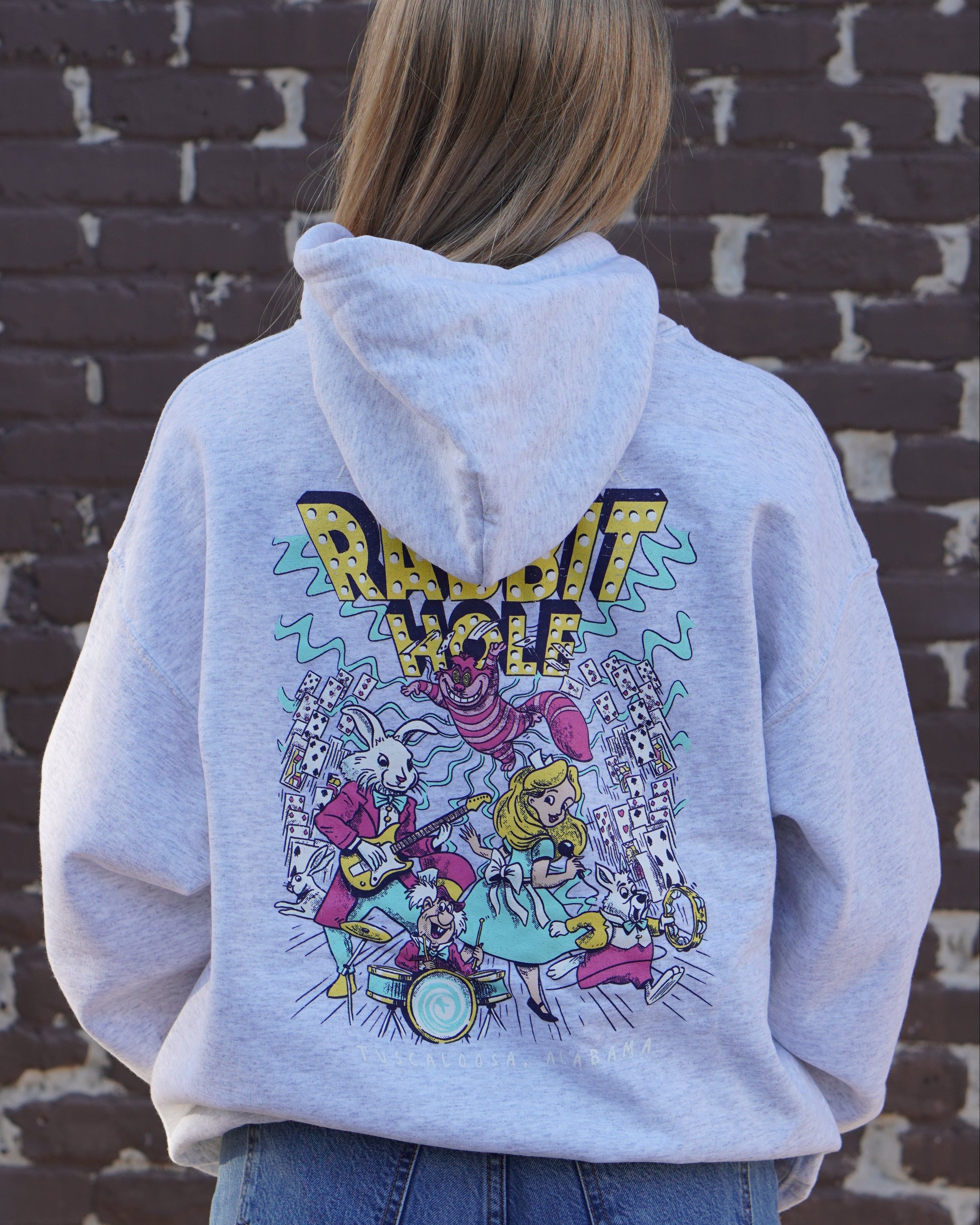 Grey Rabbit Hole Hoodie with marquee lights spelling "Rabbit Hole" lighting a band of Alice in Wonderland characters surrounded by paying cards