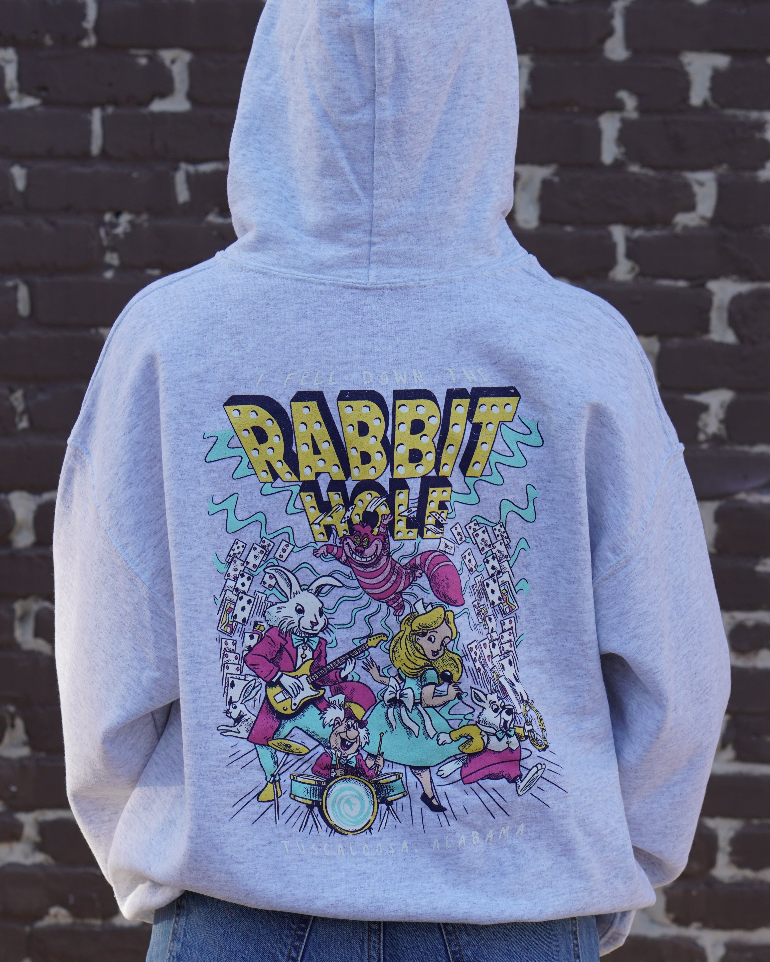 Grey Rabbit Hole Hoodie with marquee lights spelling "Rabbit Hole" lighting a band of Alice in Wonderland characters surrounded by paying cards