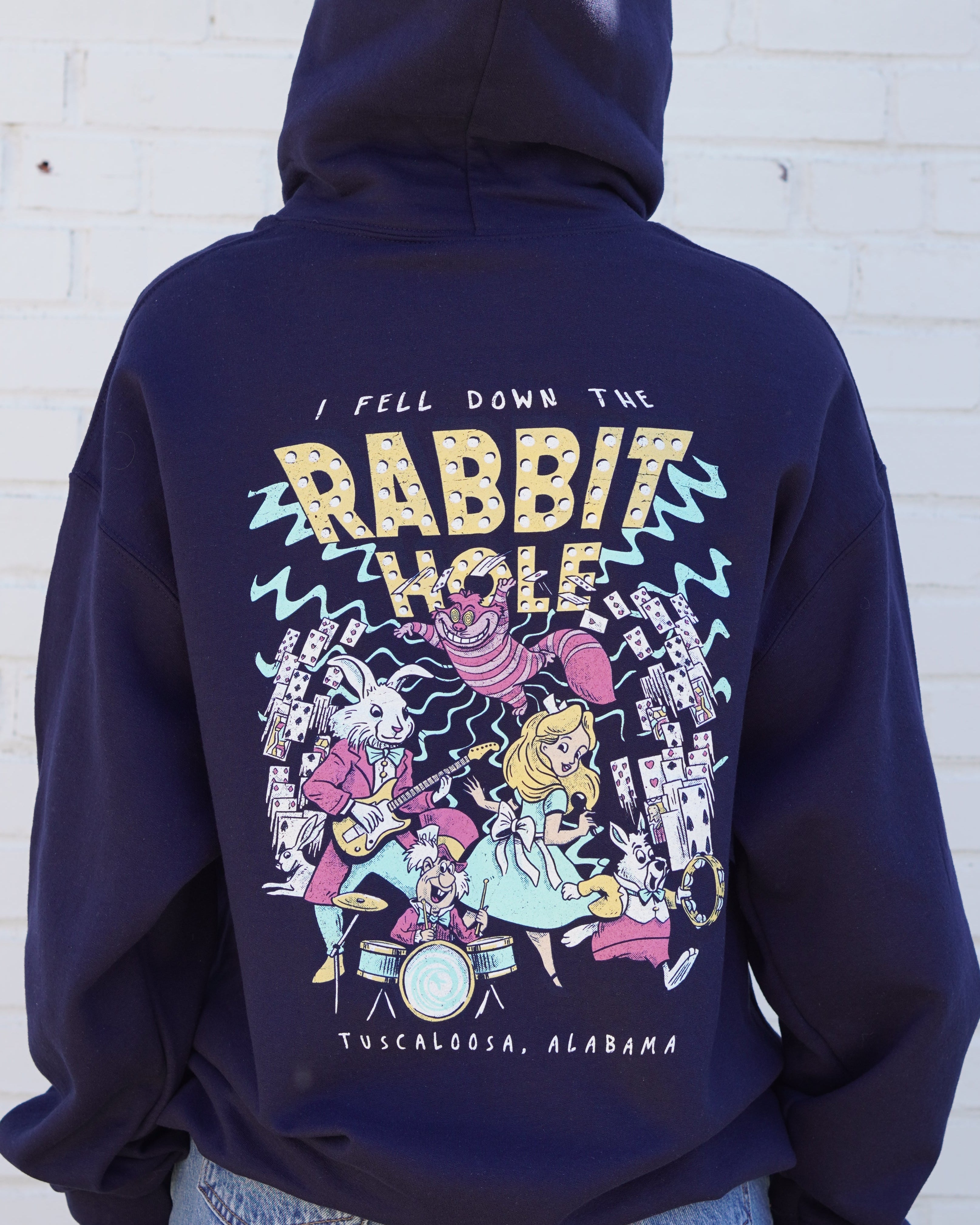 Navy Rabbit Hole Hoodie with marquee lights spelling "Rabbit Hole" lighting a band of Alice in Wonderland characters surrounded by playing cards