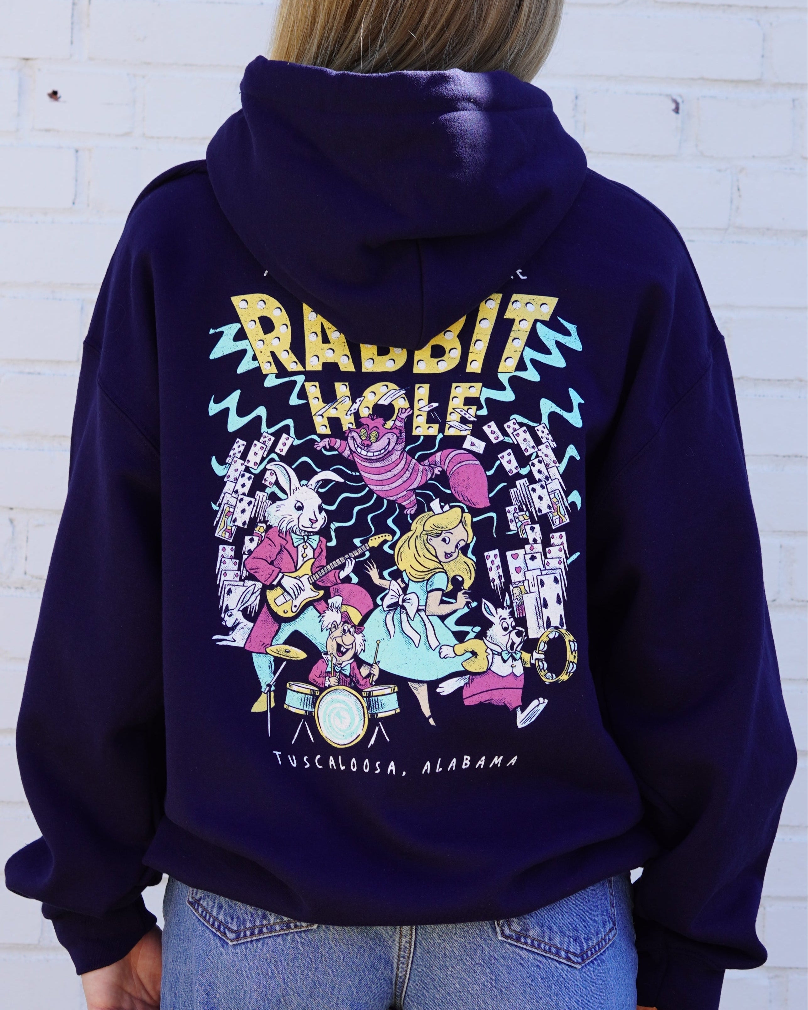 Navy Rabbit Hole Hoodie with marquee lights spelling "Rabbit Hole" lighting a band of Alice in Wonderland characters surrounded by playing cards