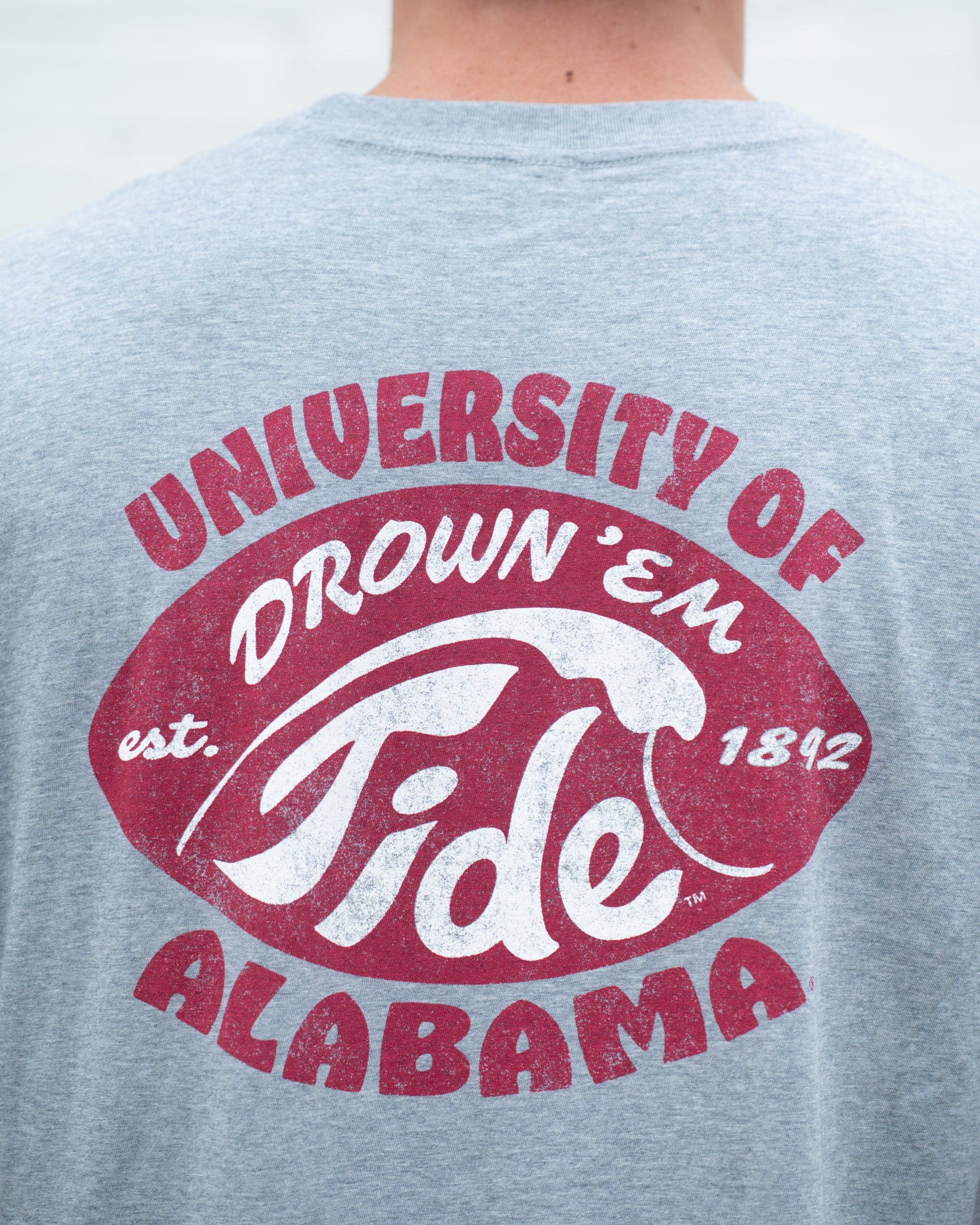 University of Alabama Gray T-Shirt with a Red football shape with a White outline of a tidal wave and White text "Drown 'Em Tide"