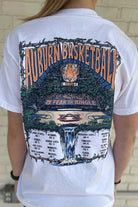 Auburn University White Fear The Jungle T-Shirt with Orange text "Auburn Basketball" and an image of the Auburn basketball court in the middle of a jungle with a waterfall spilling into the game schedule