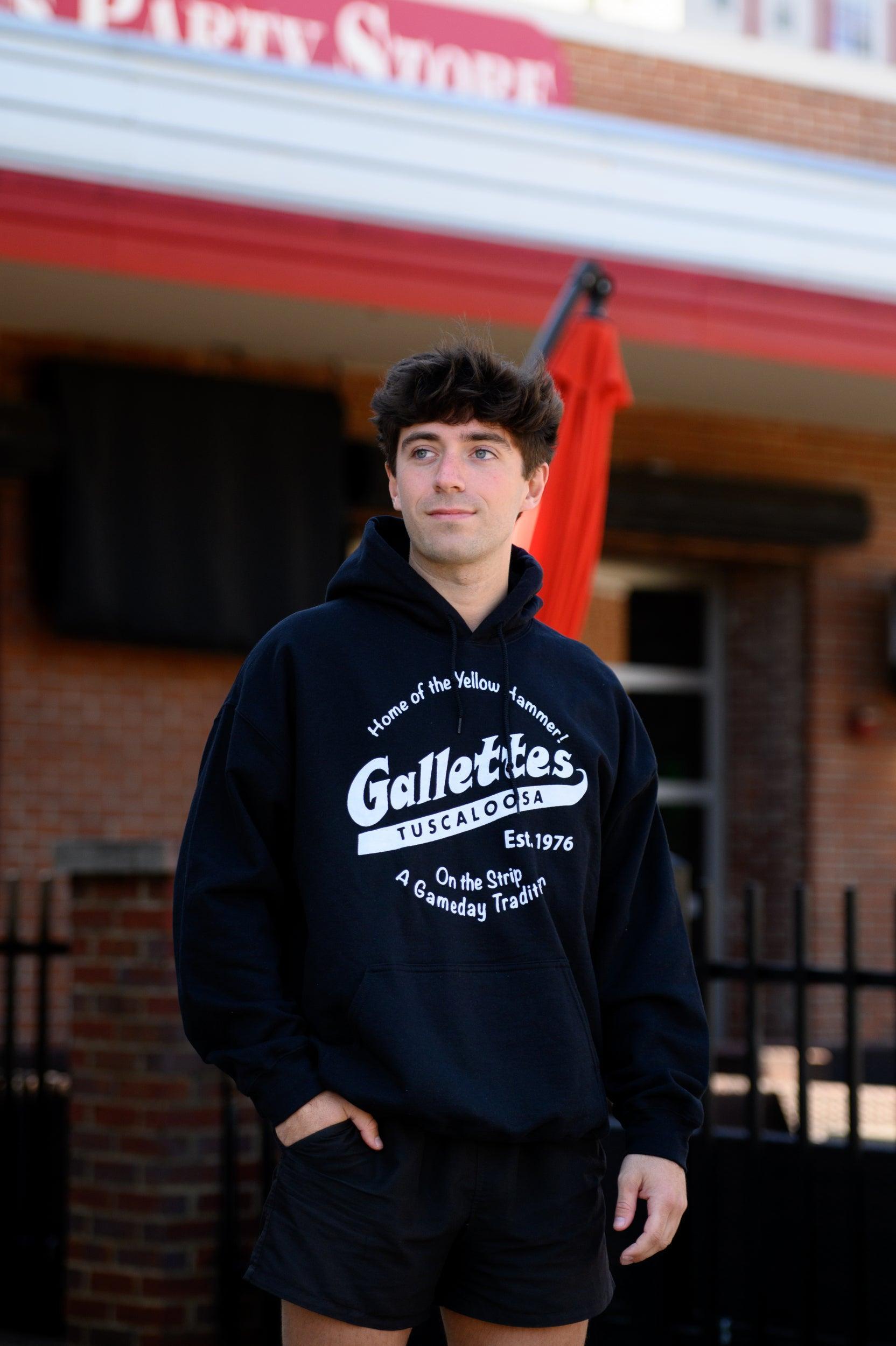 Gallettes Black Hoodie with a White Gallettes logo surrounded by White text "Home of the Yellow Hammer!" and "On the Strip- A Gameday Tradition"