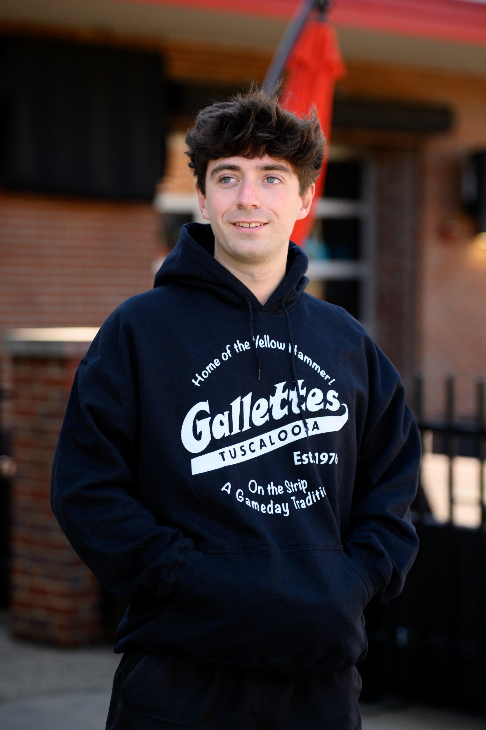 Gallettes Black Hoodie with a White Gallettes logo surrounded by White text "Home of the Yellow Hammer!" and "On the Strip- A Gameday Tradition"