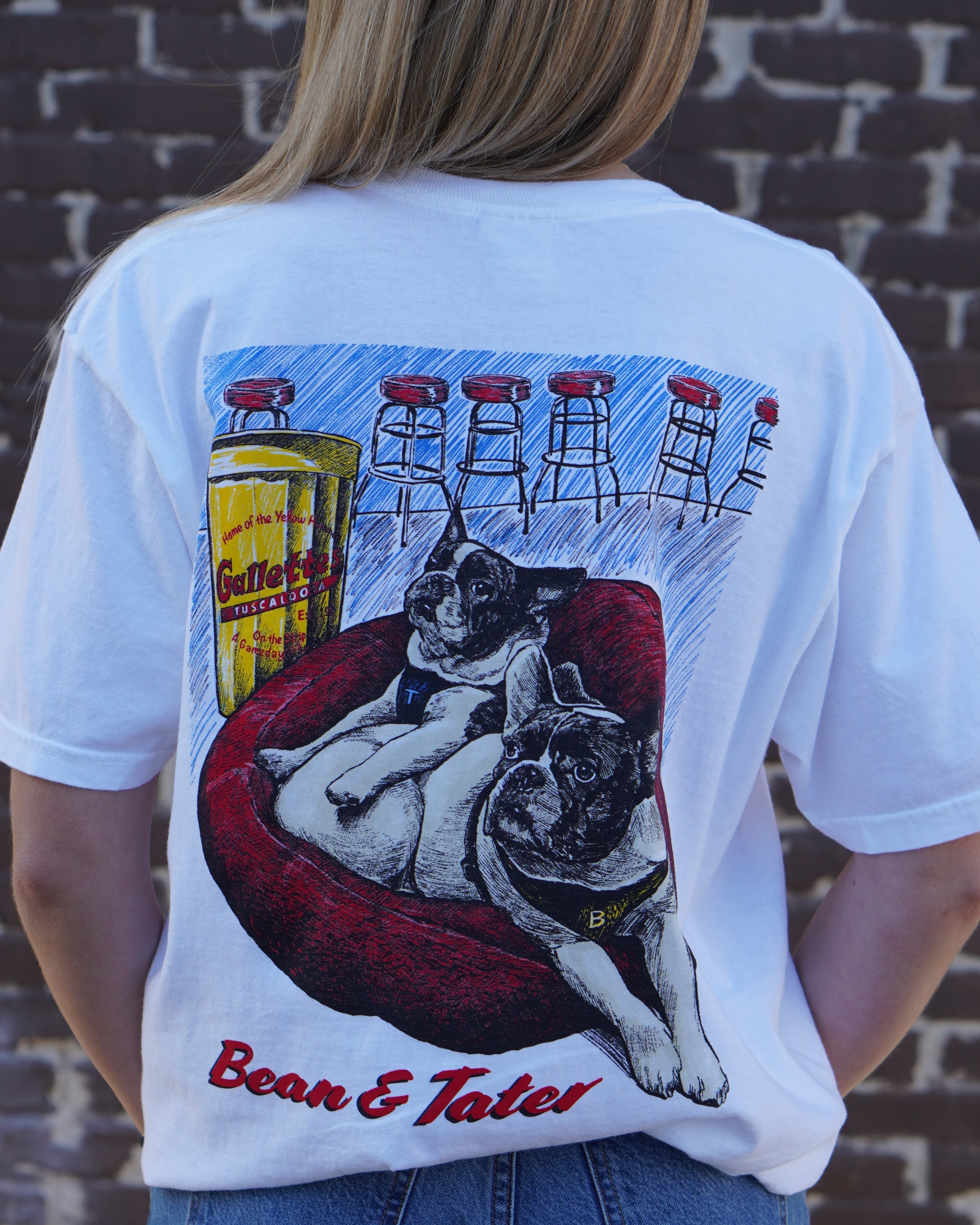 Gallettes White Tater and Bean T-Shirt with an illustration of two French bulldogs, Tater and Bean, laying down in a Red dog bed