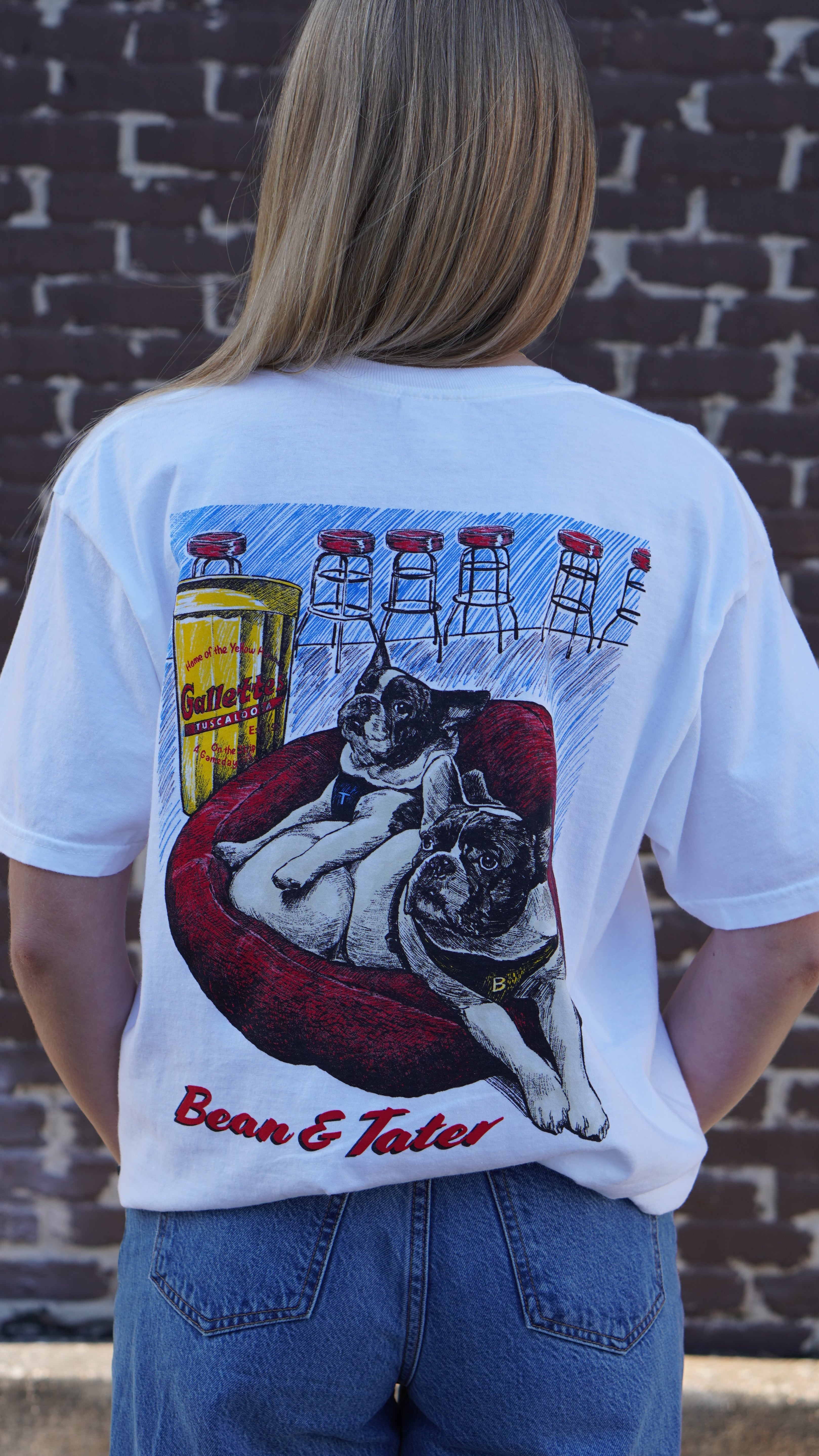 Gallettes White Tater and Bean T-Shirt with an illustration of two French bulldogs, Tater and Bean, laying down in a Red dog bed