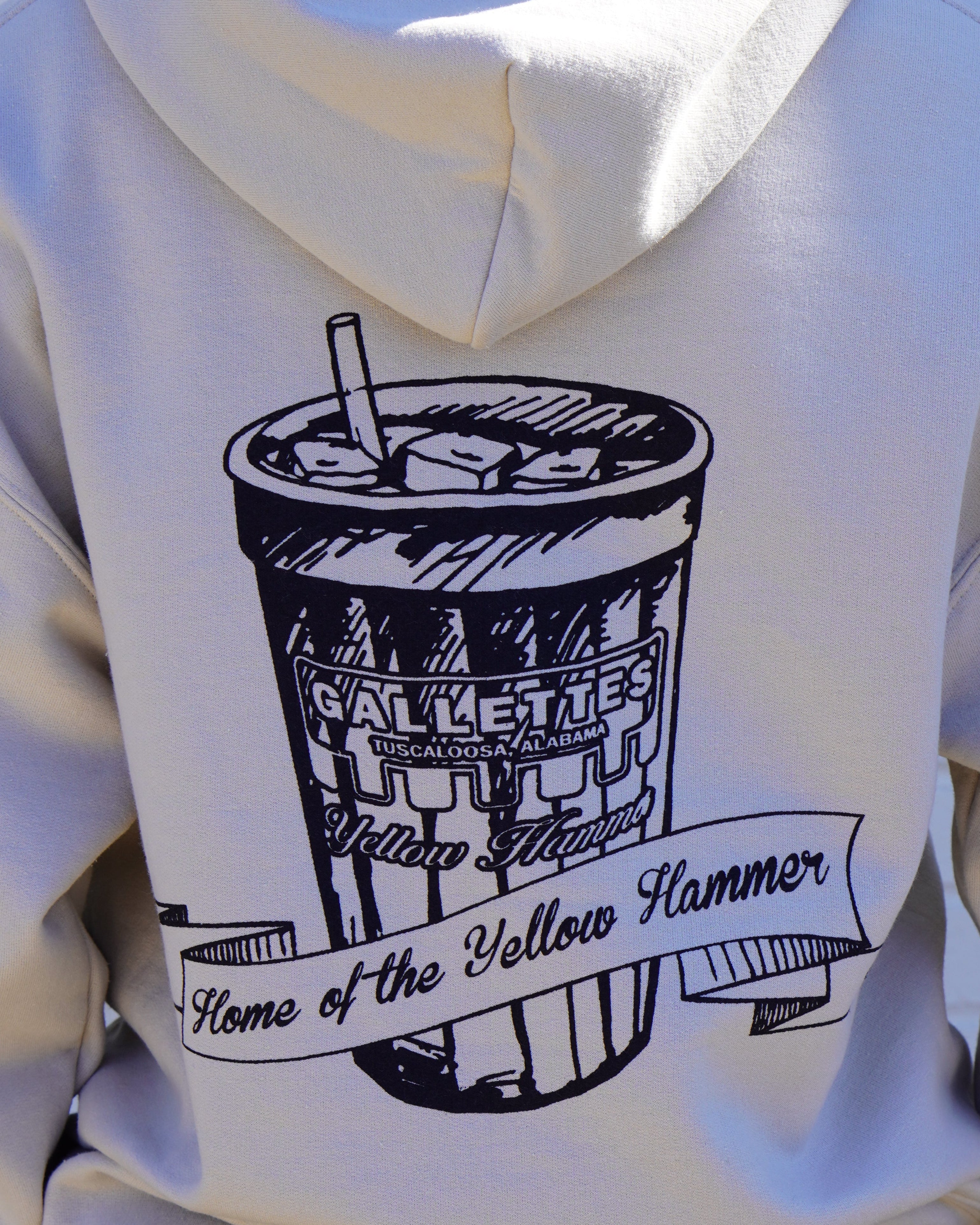 Gallettes Tan Hoodie with an illustration of a yellow hammer drink with a sash that reads “home of the yellow hammer”