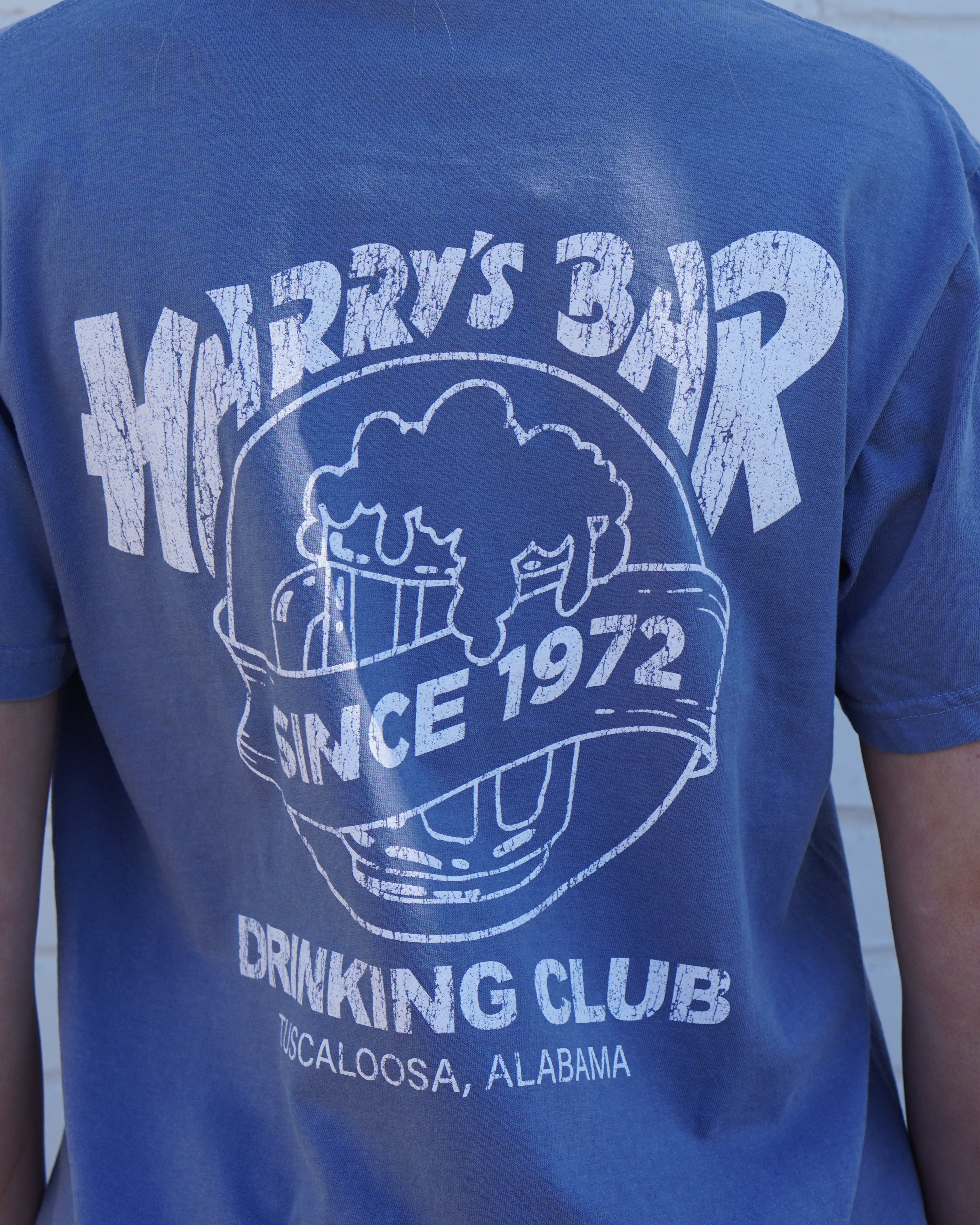 Harry’s Bar Blue T-Shirt with an image of an overflowing beer mug with a sash reading “Since 1972” above the text “Drinking Club”