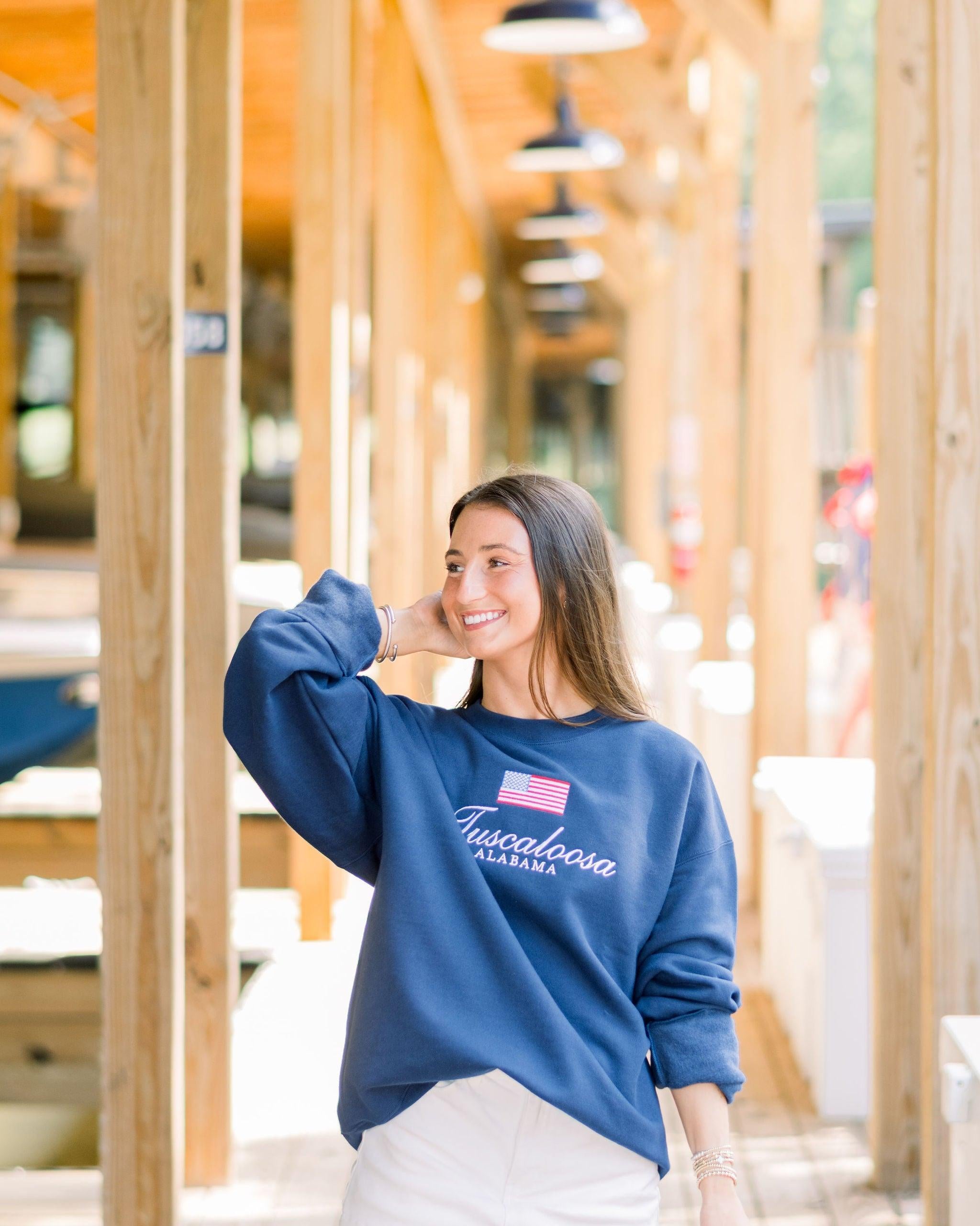 Local Merch Navy Crewneck with an embroidered American Flag above White embroidered text “Tuscaloosa Alabama”
