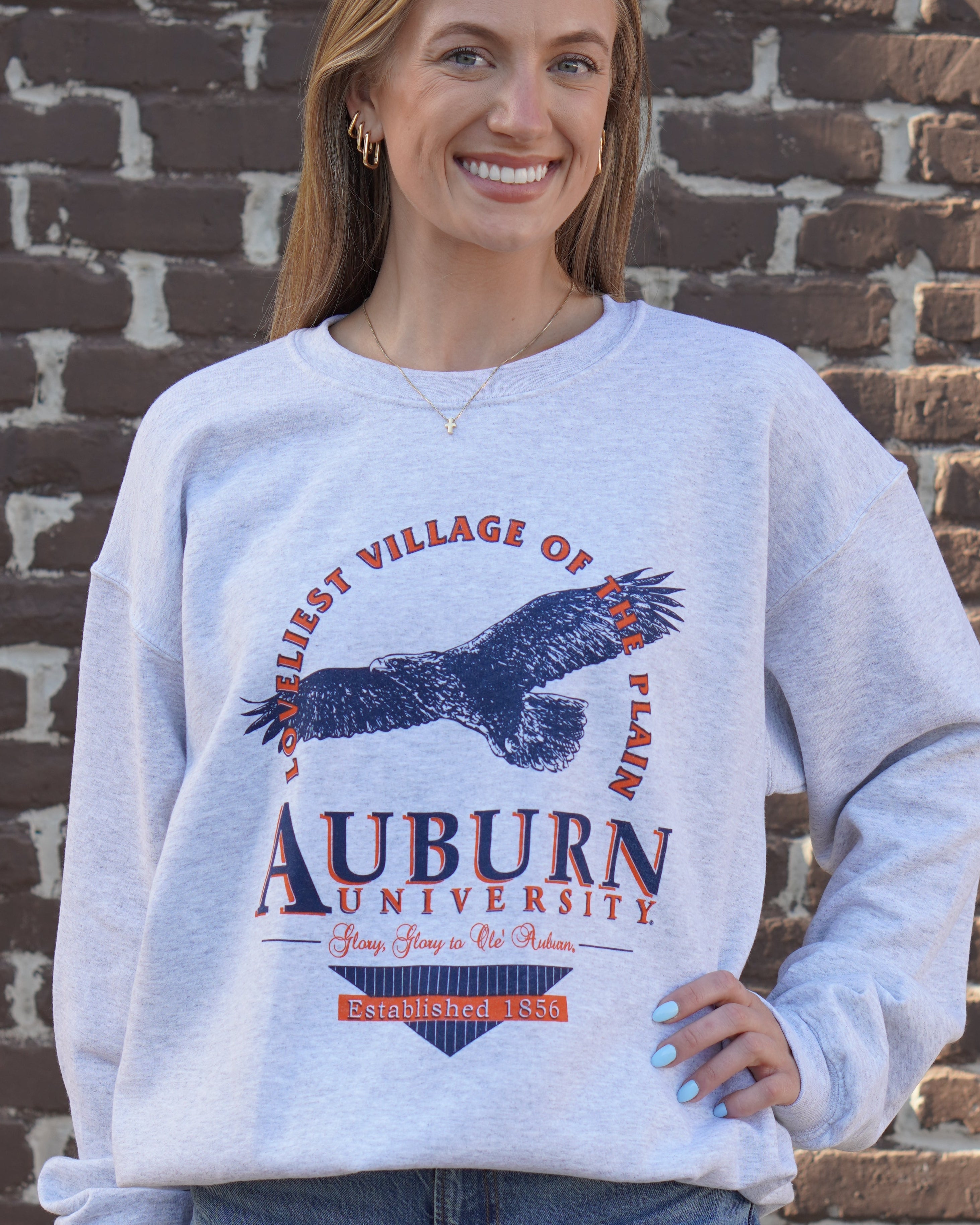 Auburn University Grey Sweatshirt with an image of an eagle flying under Orange text “Loveliest Village of the Plains” and above text “Auburn University”