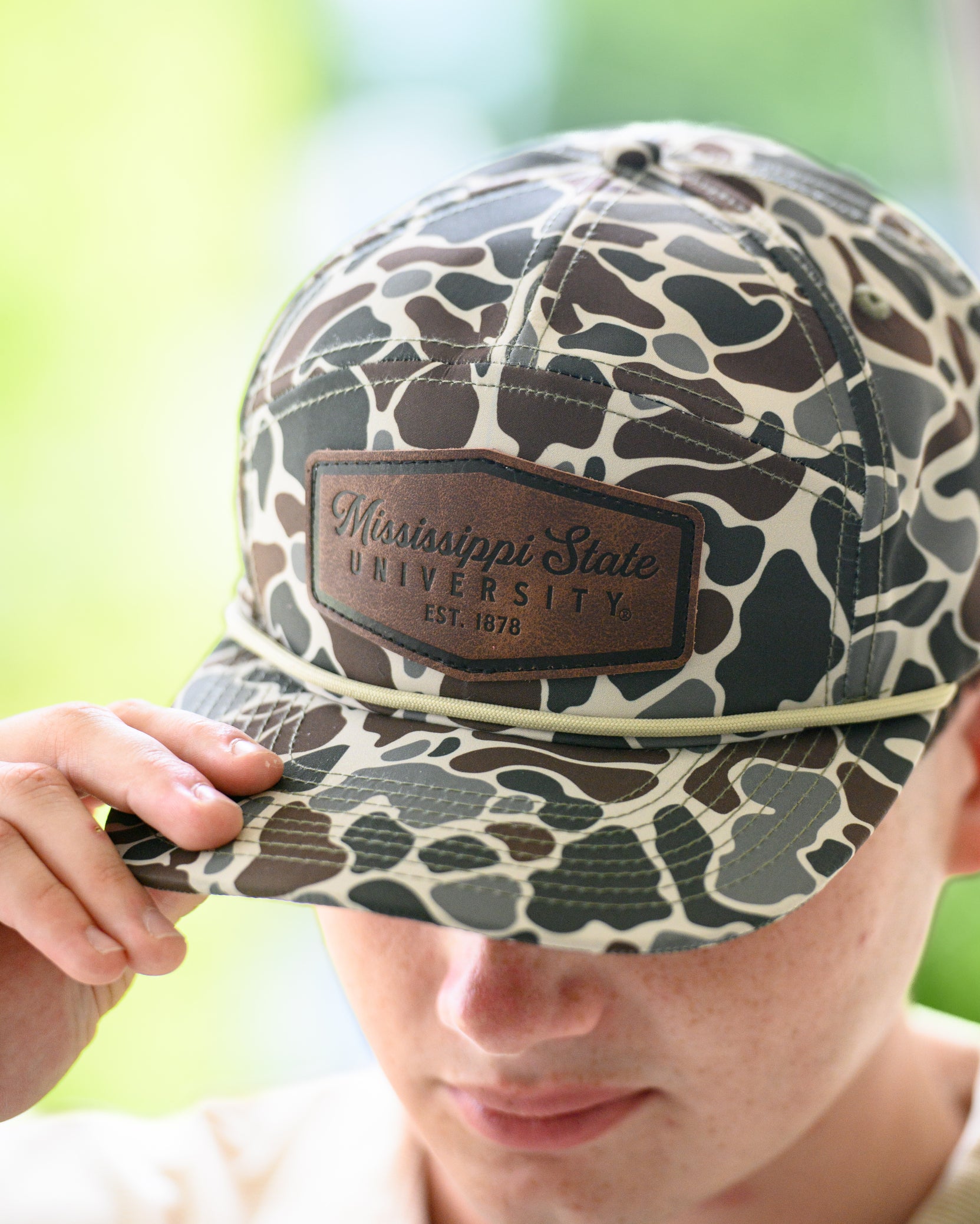 Mississippi State Camo Hat with a White rope and a leather patch with text “Mississippi State University”